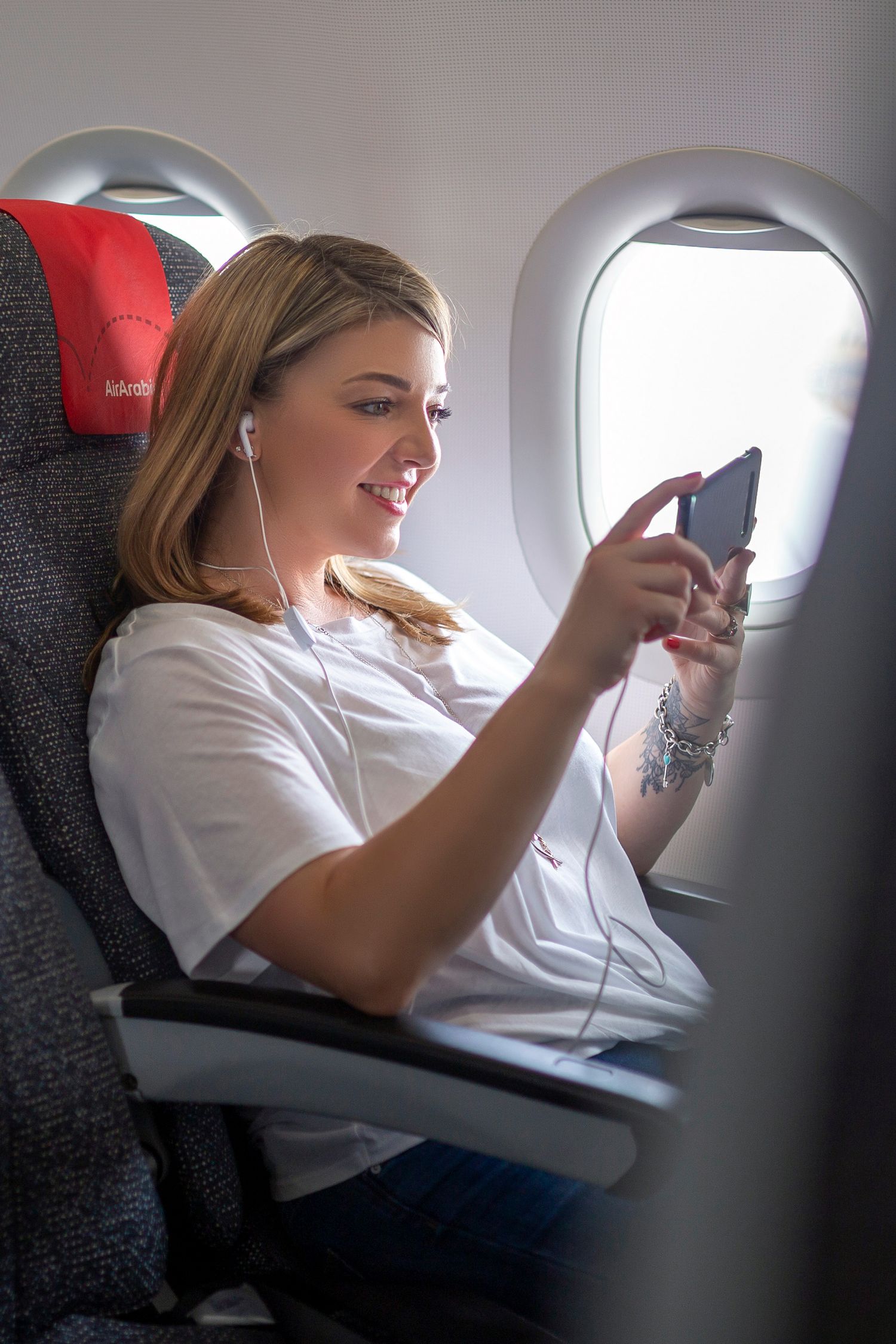 Airplane passenger seated by a window using a mobile phone, produced for creative visual content.