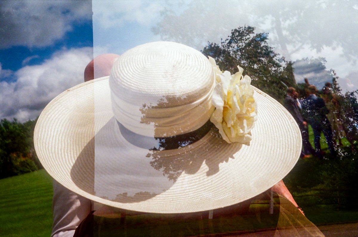 Elegant wide-brim cream wedding hat with floral detail against a blue sky backdrop.