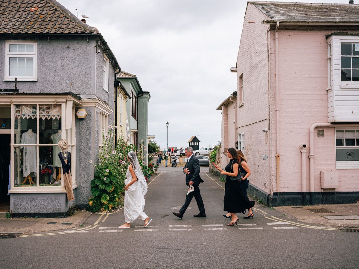 Wedding party crossing a zebra crossing on a quaint English coastal village street.