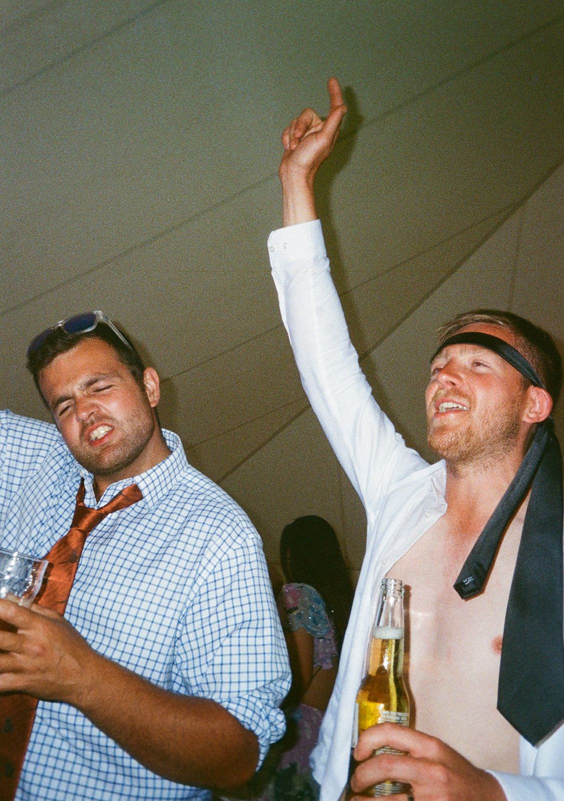Two wedding guests dancing and celebrating at lively indoor wedding reception.
