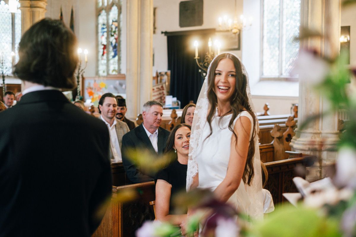 Bride smiling joyfully at the altar during her wedding ceremony in a church.