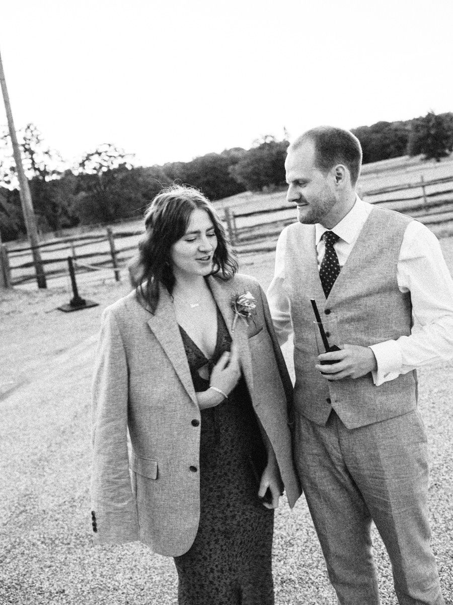 Black and white photo of couple sharing a smile at outdoor wedding venue.
