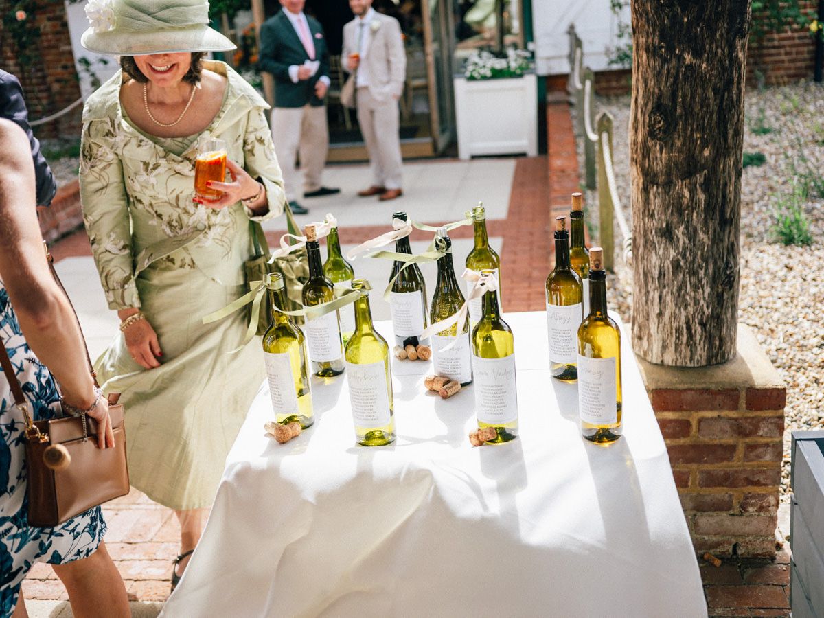 Elegant outdoor wine display on white tablecloth at a sunny garden wedding reception.