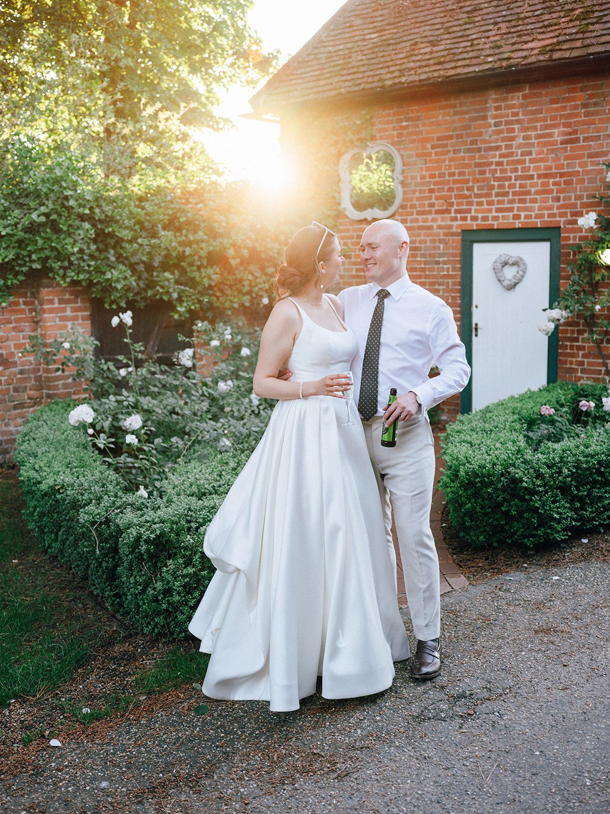Bride and groom sharing a romantic moment outside a brick building at golden hour.