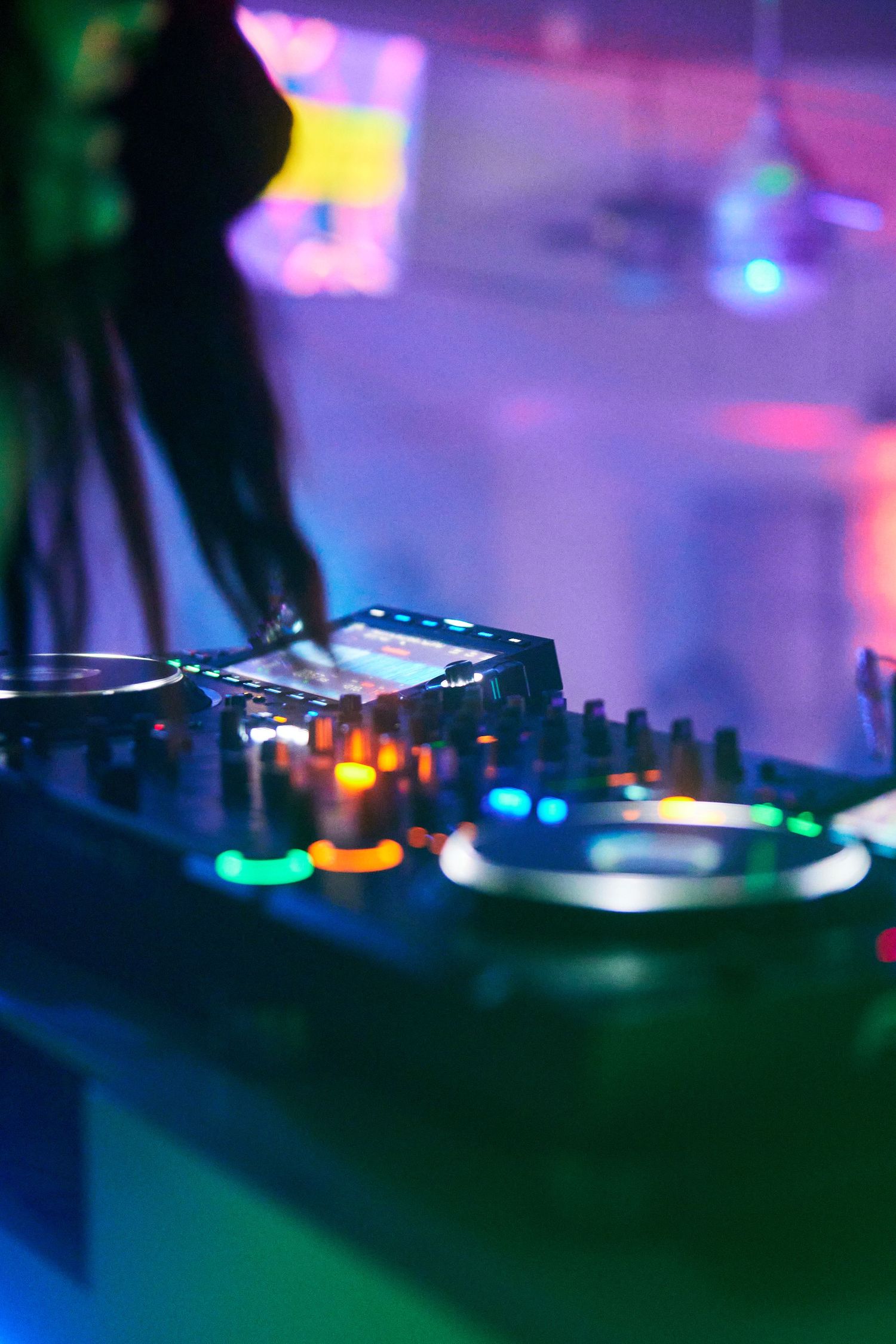 DJ equipment with colorful lights in nightclub setting.