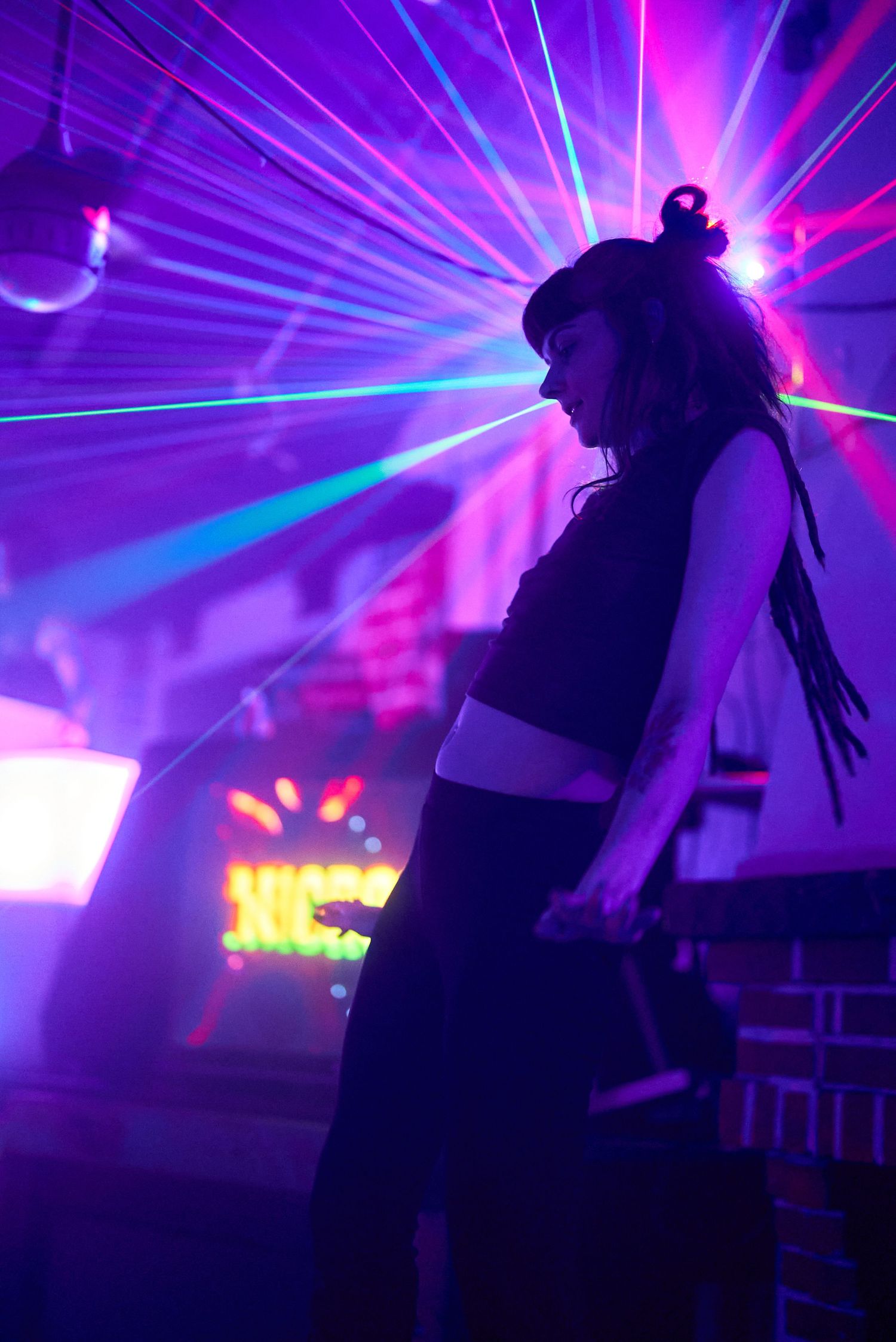 Silhouette of dancer in club with purple laser lights creating dramatic atmosphere.