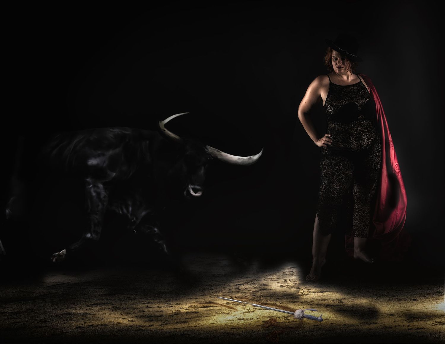 A woman in a black dress holds a red cape facing a dark bull in a dramatic bullfighting scene.