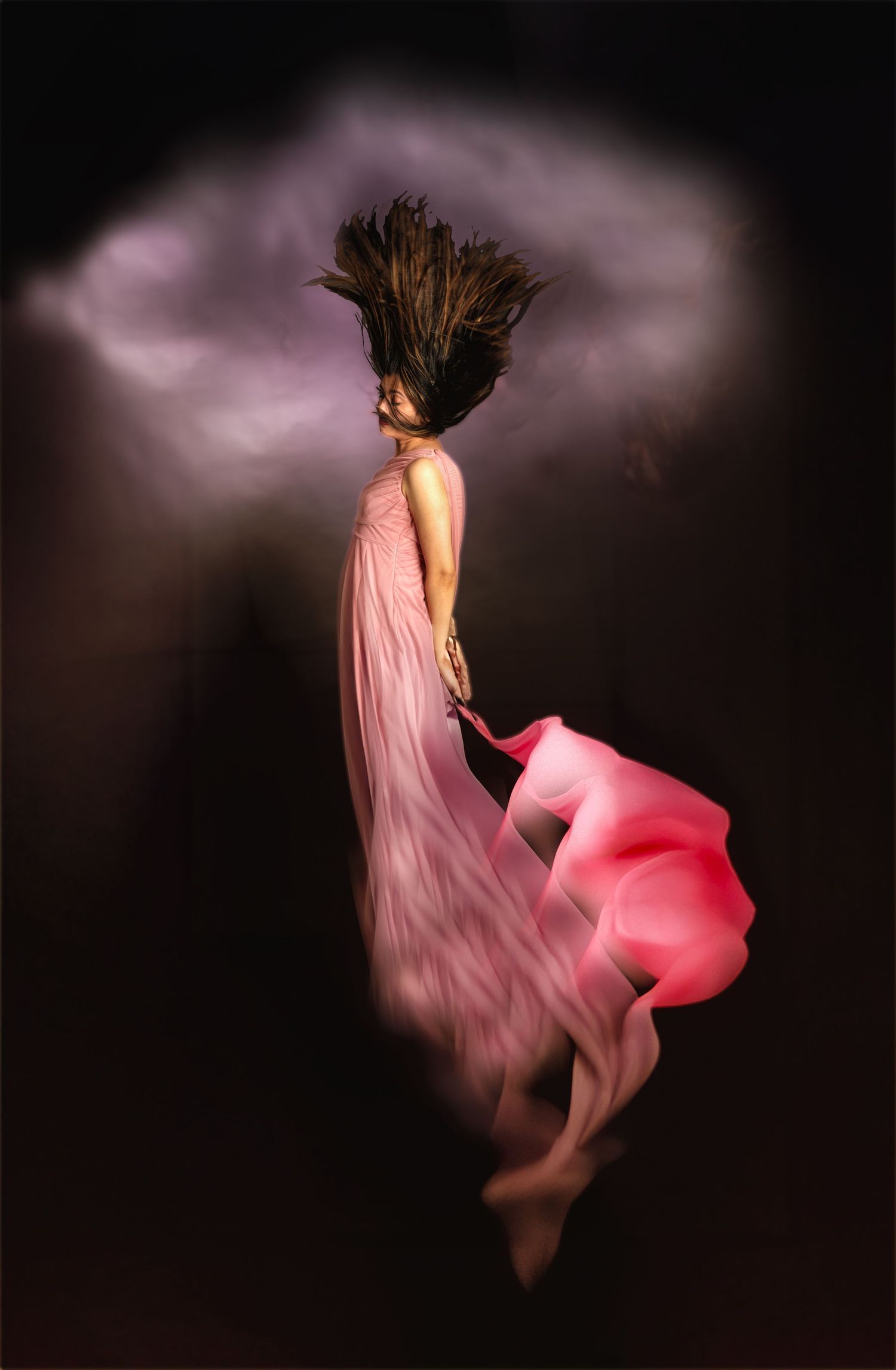 Fine art portrait of a woman in motion wearing a flowing pink dress against a dark background, with soft, ethereal movement and dramatic lig
