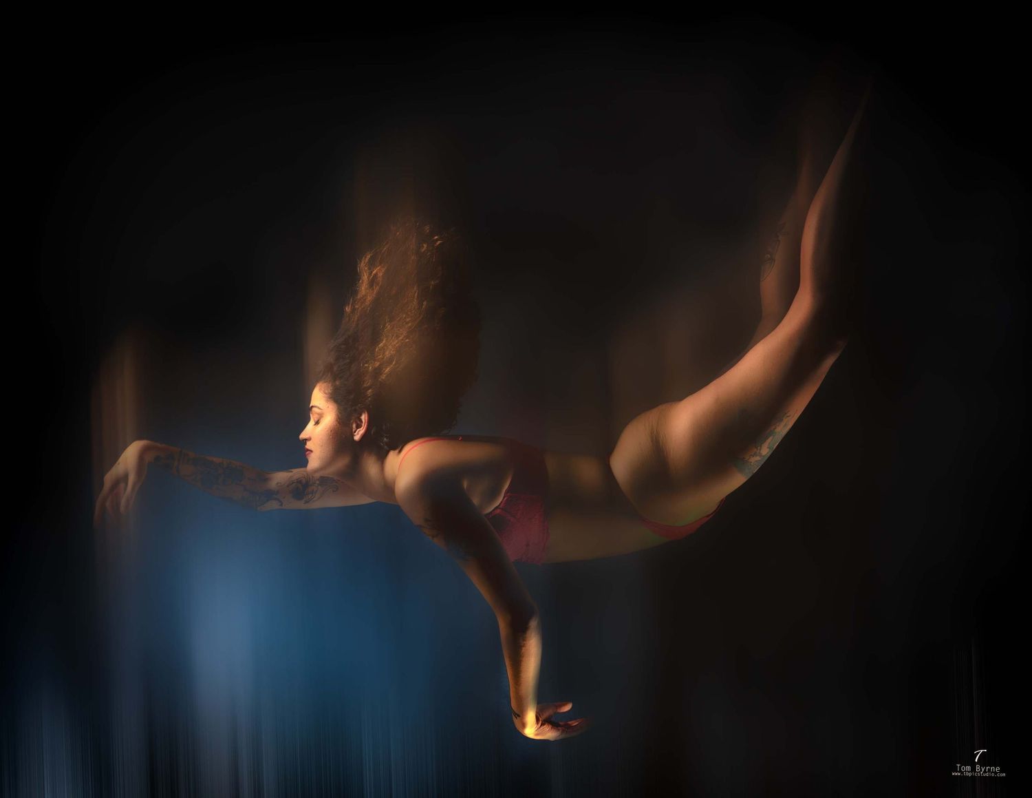 A woman in a pink bikini gracefully dives underwater, her hair flowing freely in a dramatic, artistic underwater photograph.