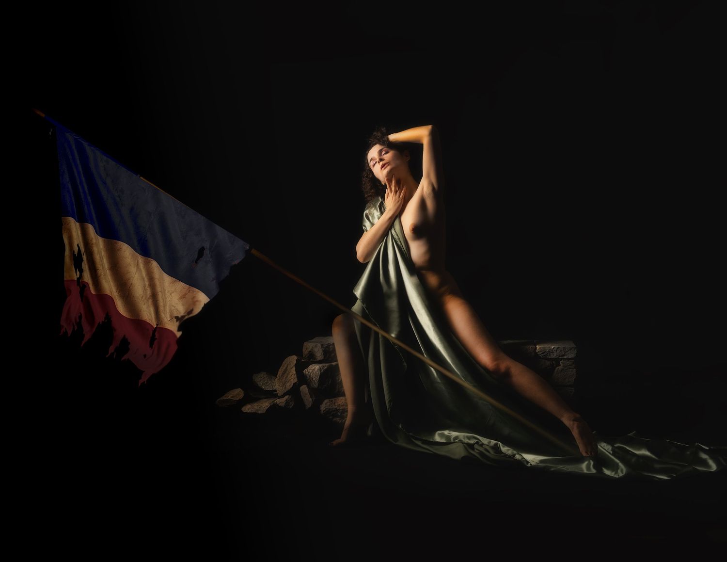 A woman draped in green fabric poses dramatically beside a tricolor flag against a dark background.