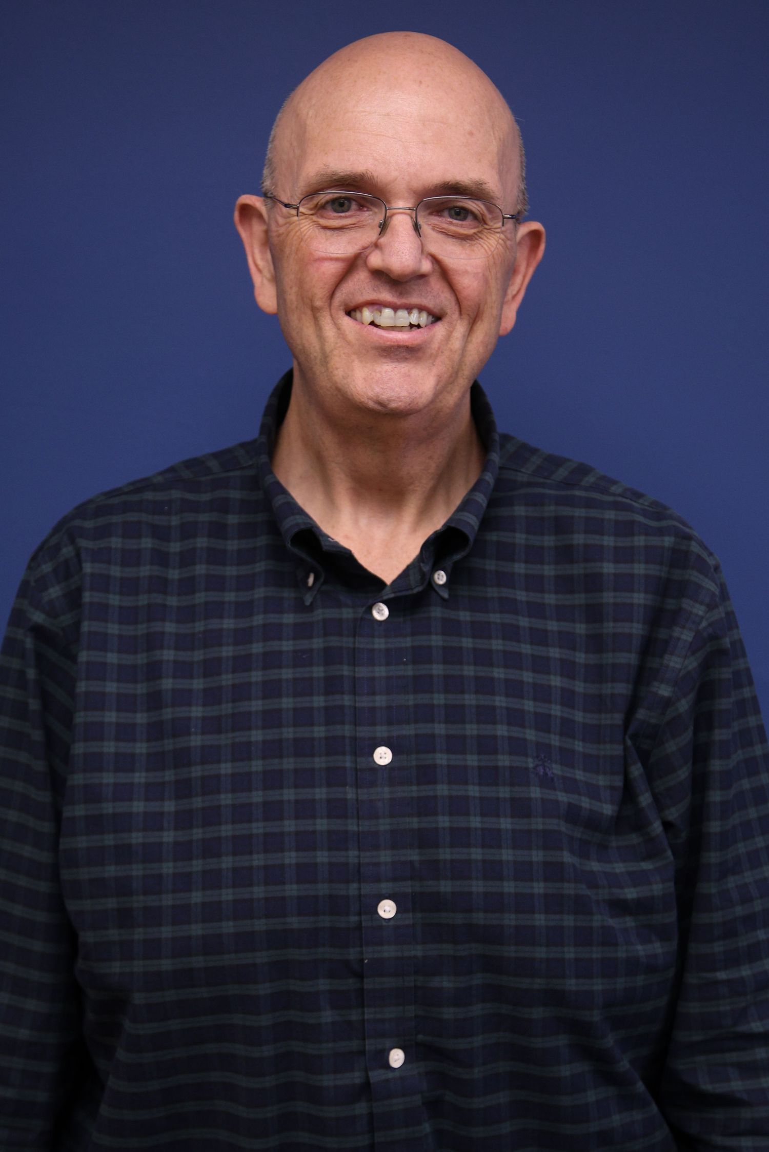 Portrait of photographer Brendan O’Byrne smiling against blue studio background