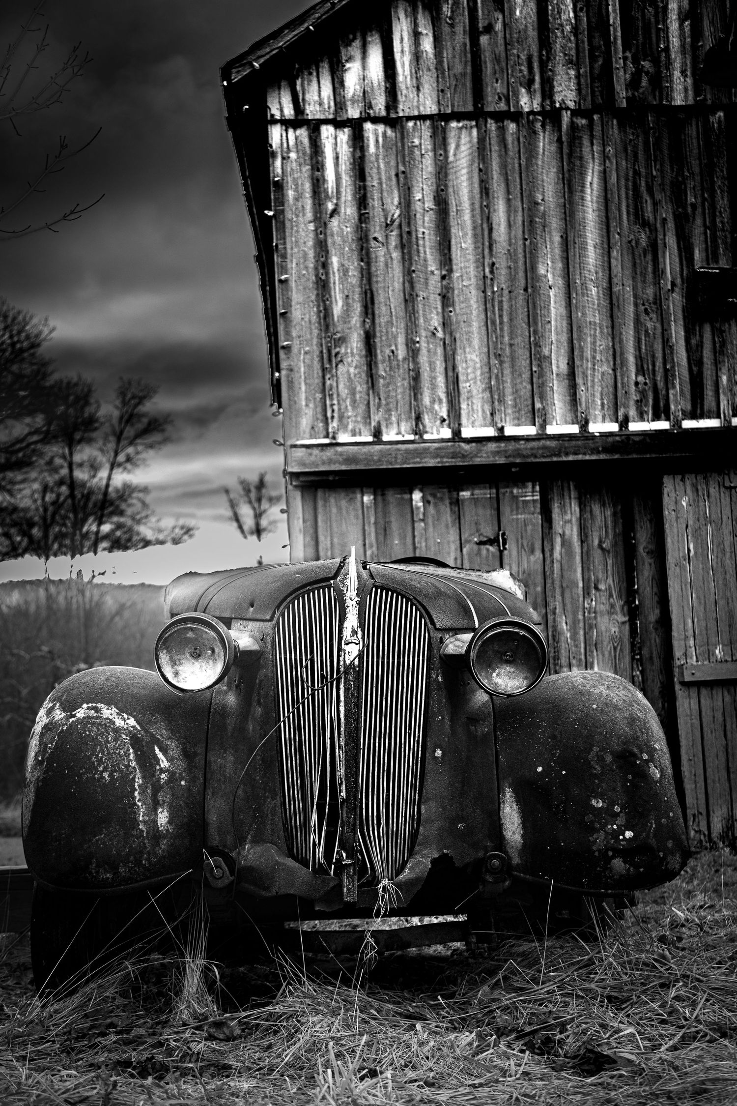 Abandoned vintage car in front of weathered barn in Columbia NJ, black and white rural scene