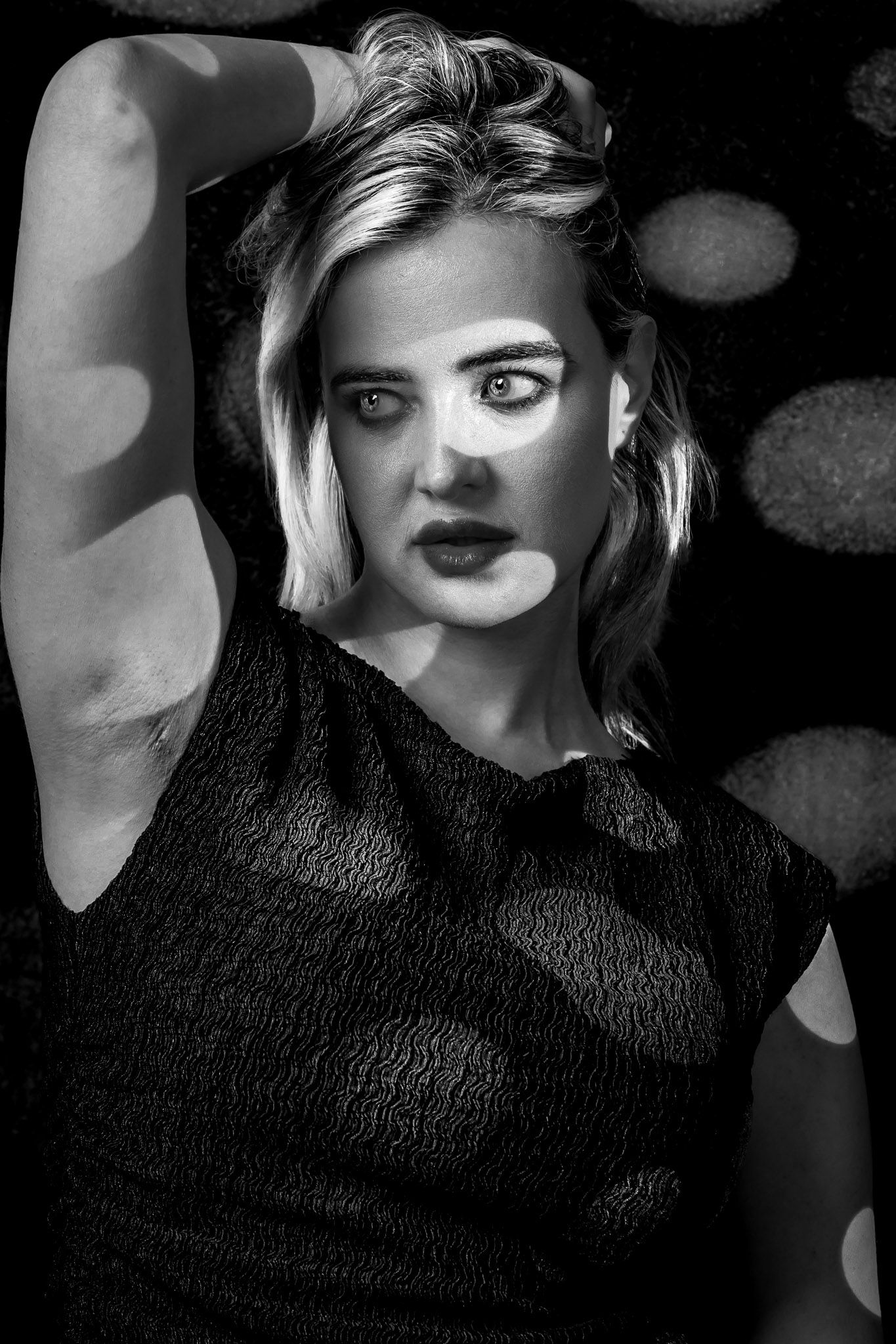 Black and white studio portrait of a woman with dramatic patterned light and shadow across her face and body. during a Unique Photo photogra