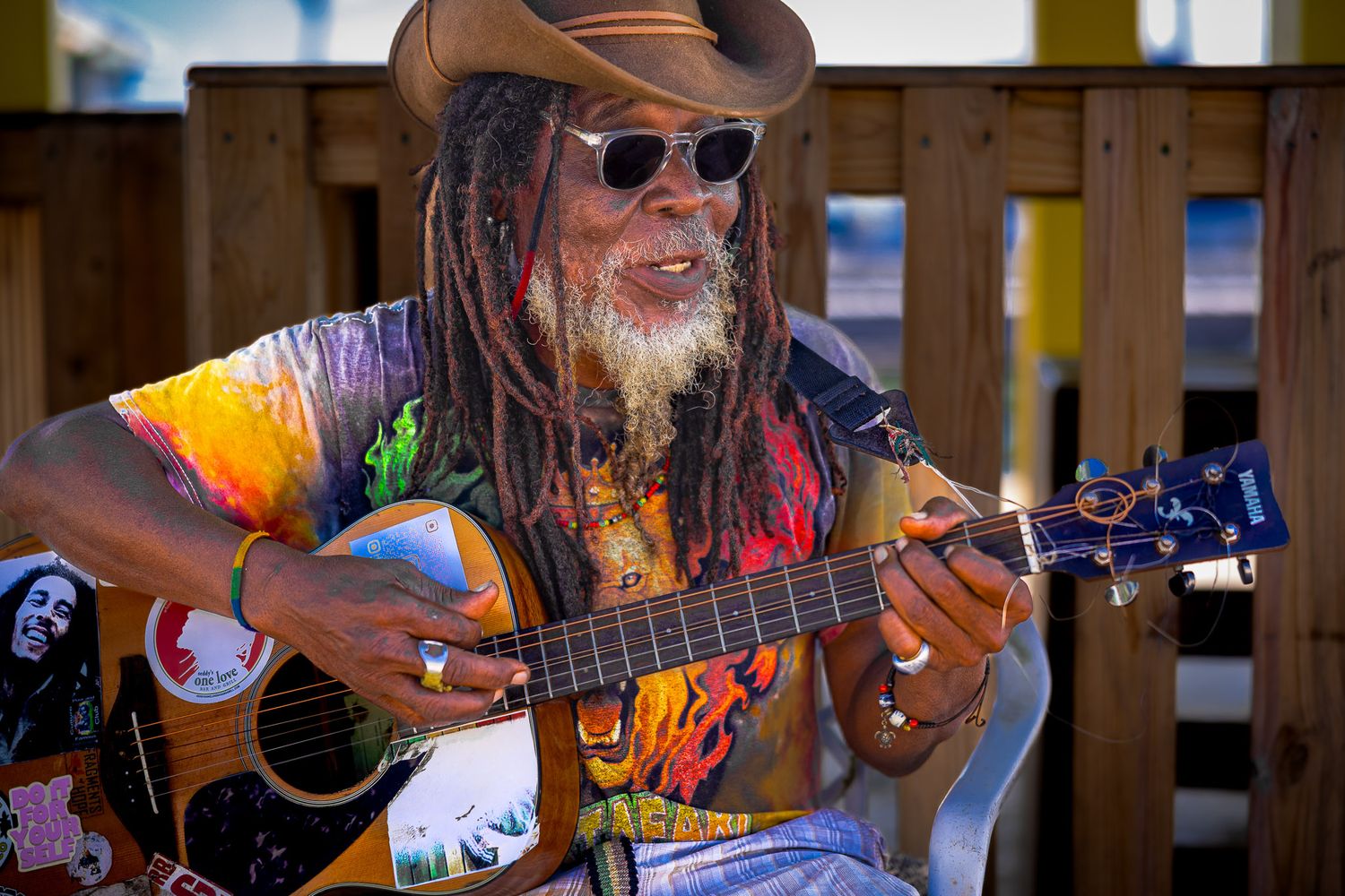 Street portrait of a musician playing guitar in Placencia, Belize, captured in natural light with vibrant color and character.