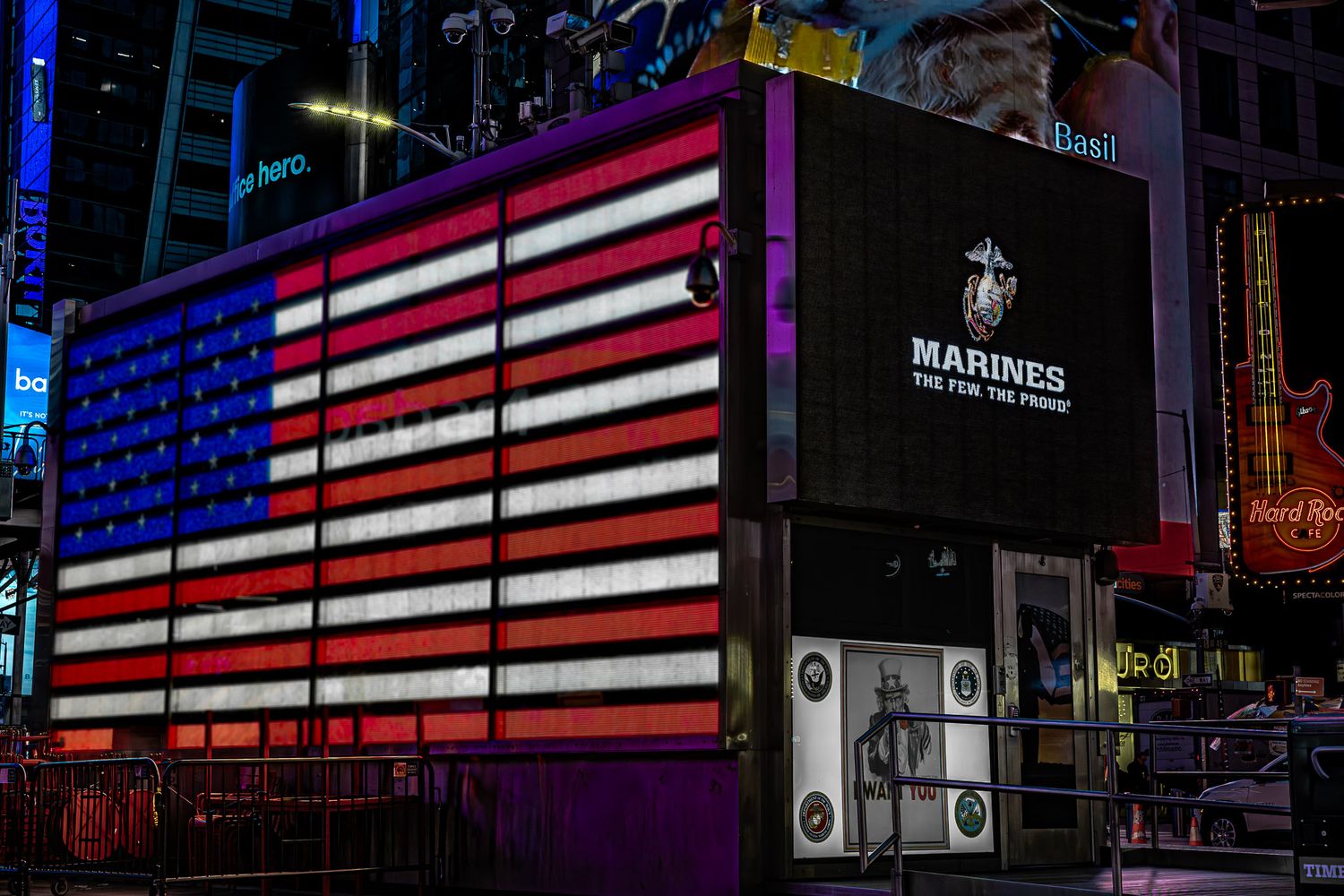 Times Square at night featuring a massive illuminated American flag display and U.S. Marines digital billboard.