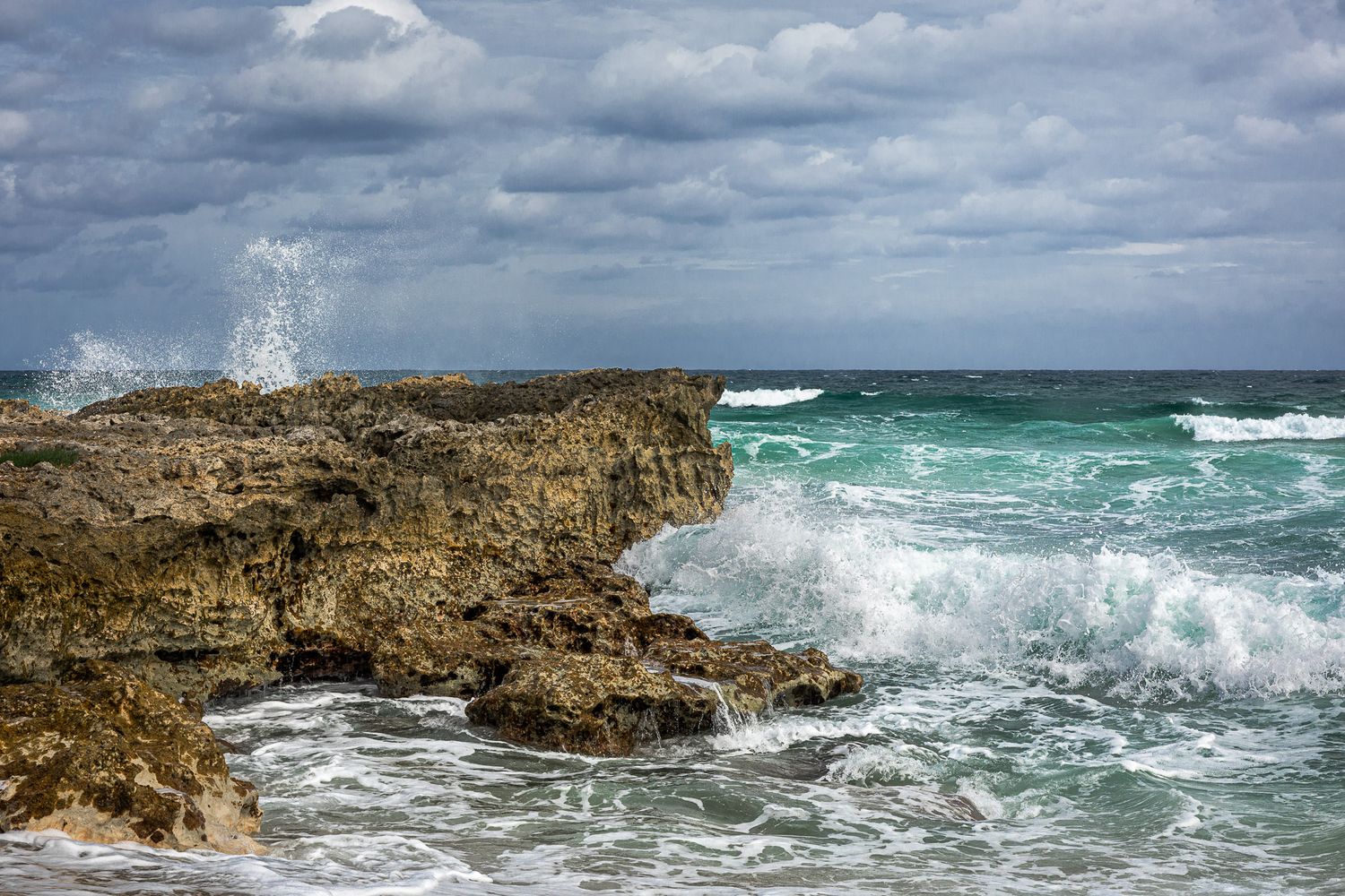 Waves crashing against rocky coastline in Cozumel, Mexico under overcast skies
