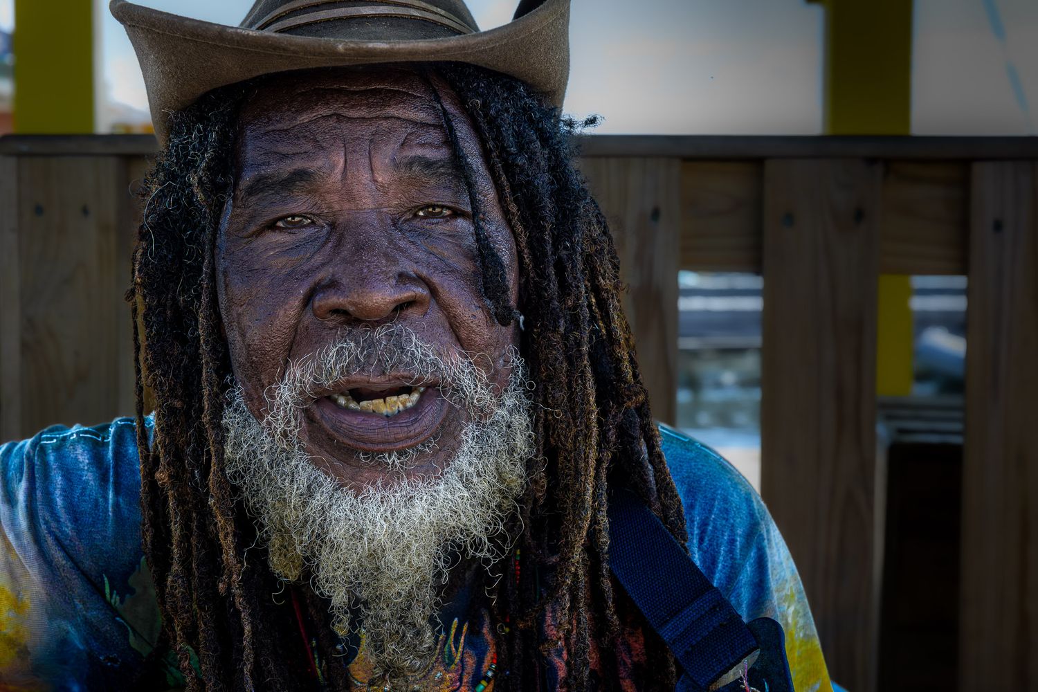 Street portrait of a local musician with dreadlocks and hat in Placencia, Belize, playing guitar and singing along the waterfront.