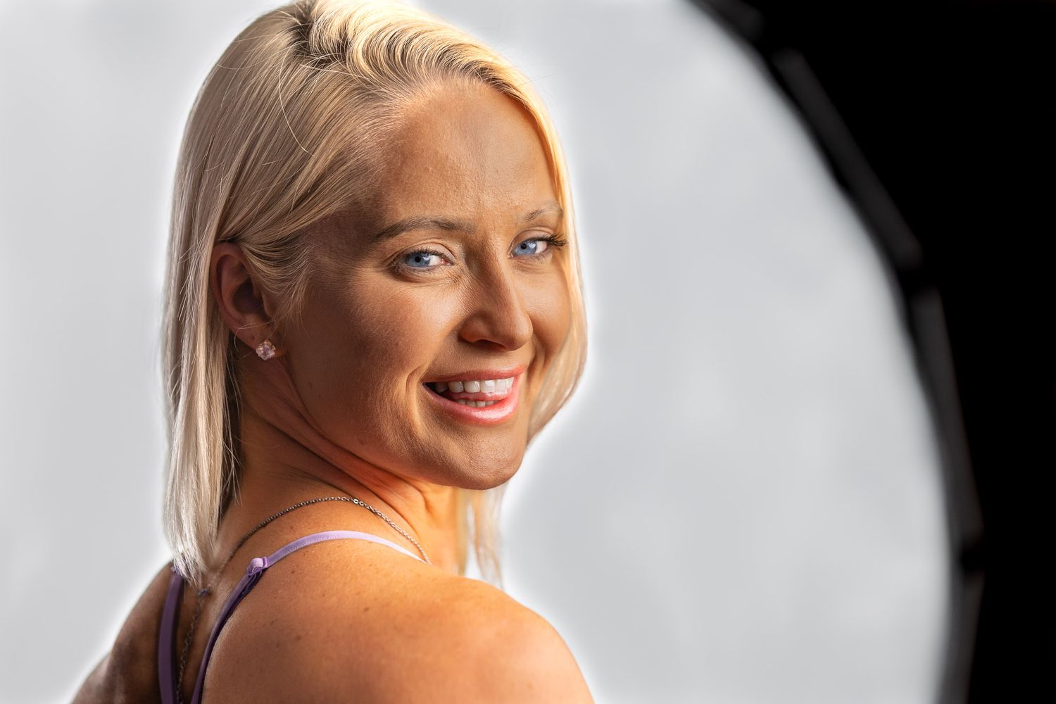 Studio portrait of smiling blonde woman looking over shoulder with soft professional lighting during a Unique Photo photography event in New