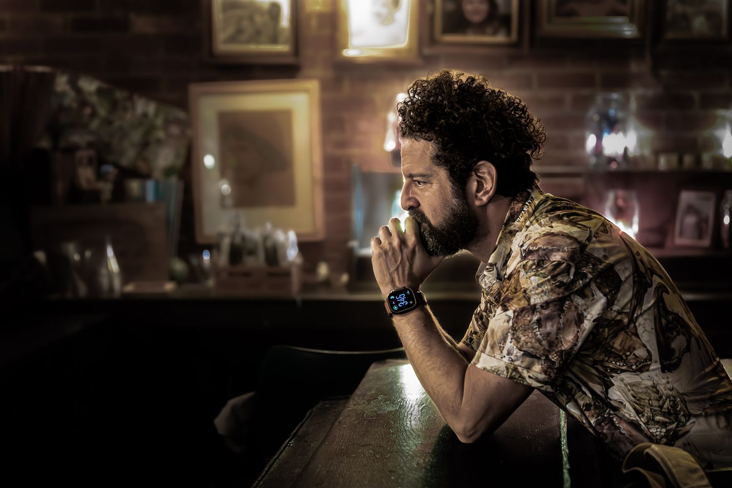 Man seated at a bar in a dim basement setting, photographed candidly during a quiet moment in Philadelphia, PA.
