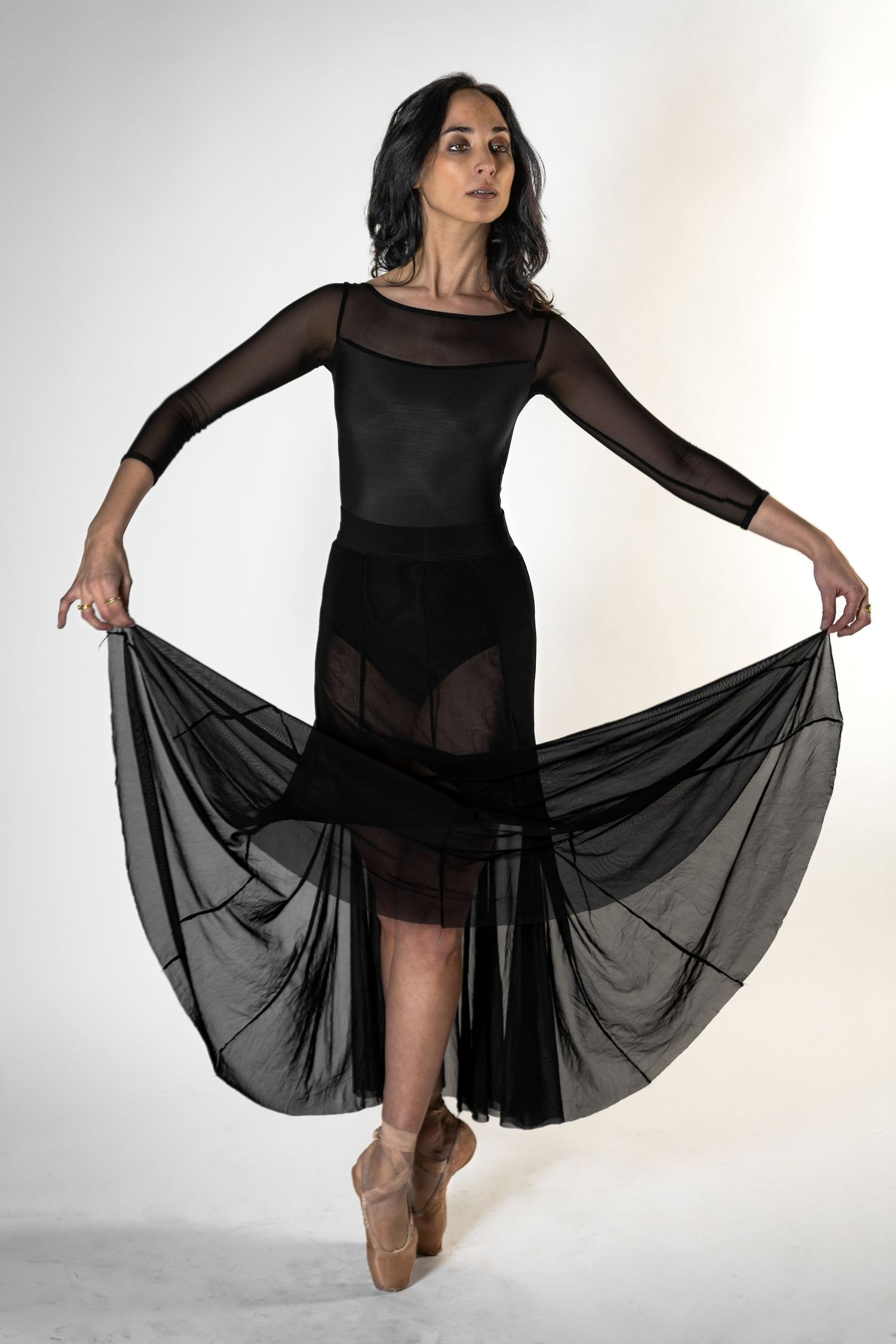 Ballet dancer posed en pointe in a black sheer dress during a studio portrait session in Fairfield, New Jersey.