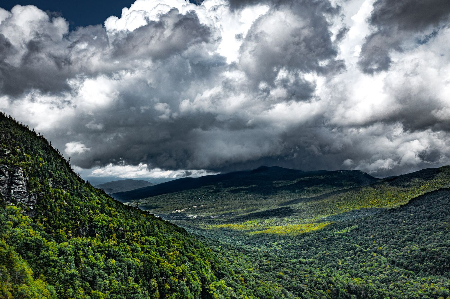 Aerial view of Smugglers' Notch in Vermont with dramatic storm clouds and sunlight breaking over the Green Mountains.