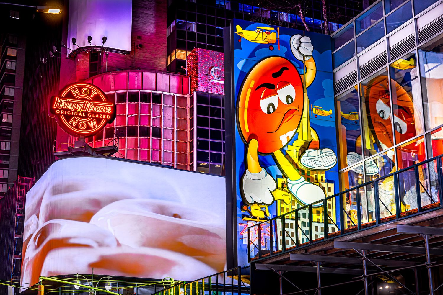Times Square street photography featuring neon Krispy Kreme sign and colorful M&M’s billboard at night.