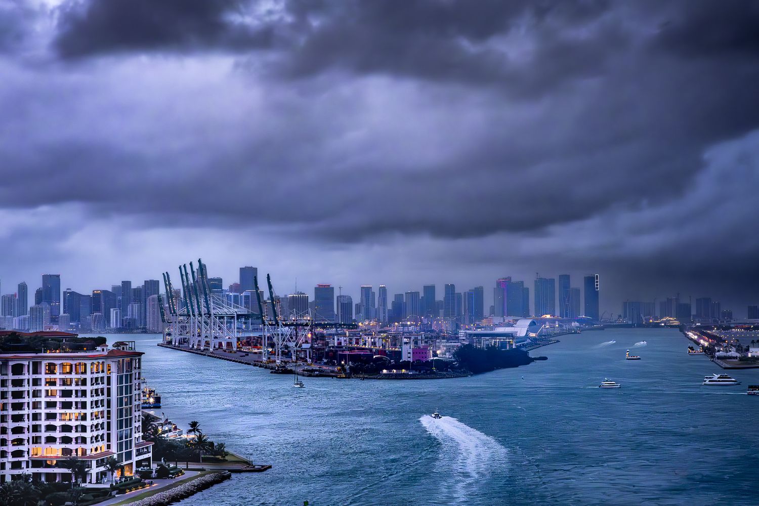 Miami skyline under storm clouds as Norwegian Bliss departs port, dramatic evening light over Biscayne Bay