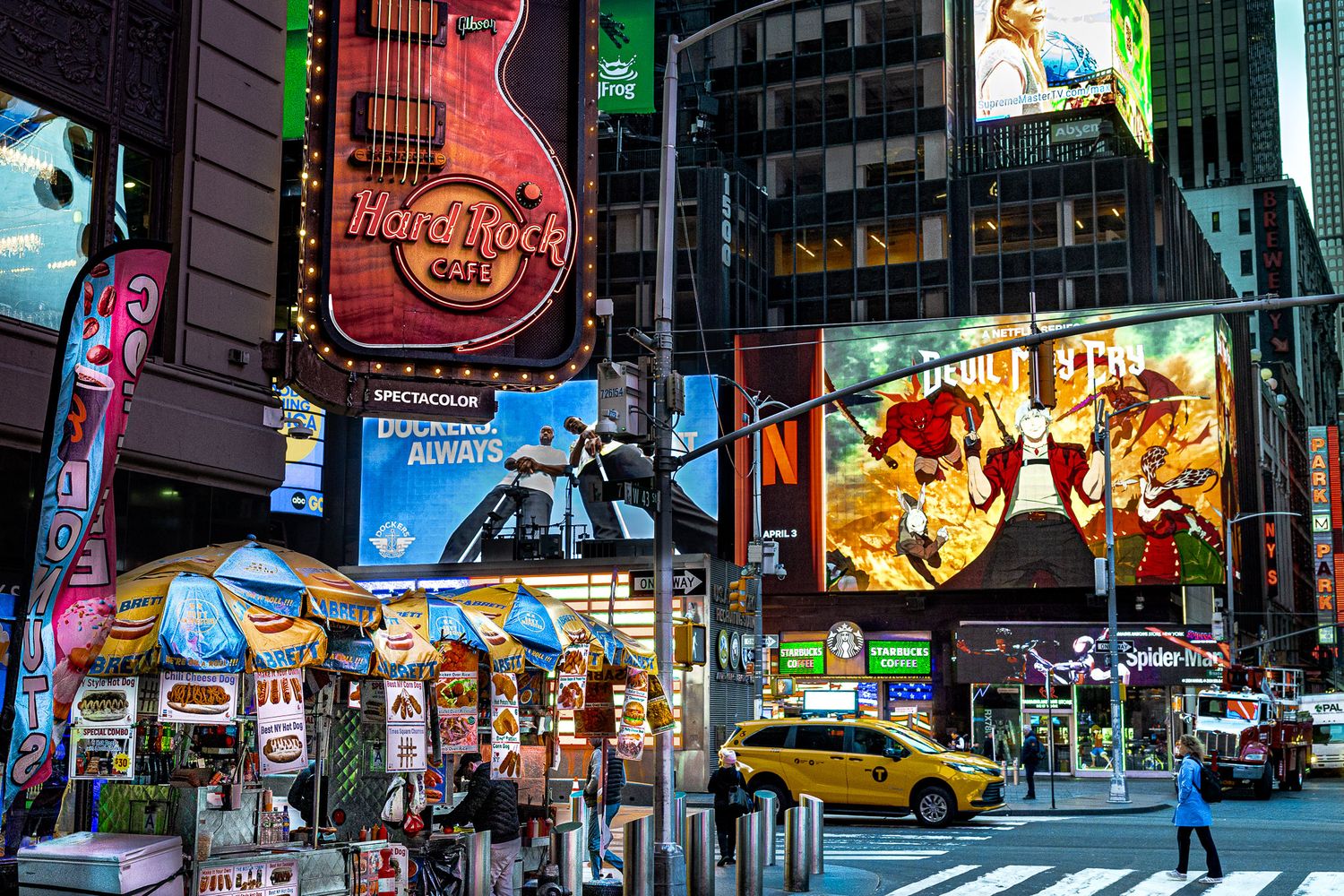 Street photography of the Hard Rock Cafe guitar sign illuminated at night in Times Square, New York City.