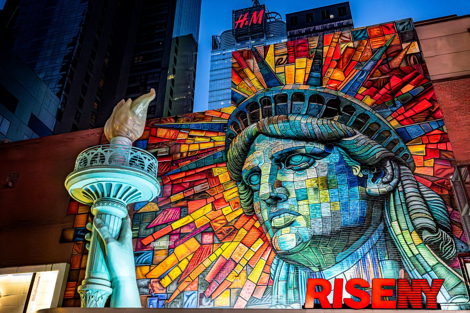 Street photography near Times Square featuring the RiseNY Statue of Liberty mural by artist Jenna Morello at night.