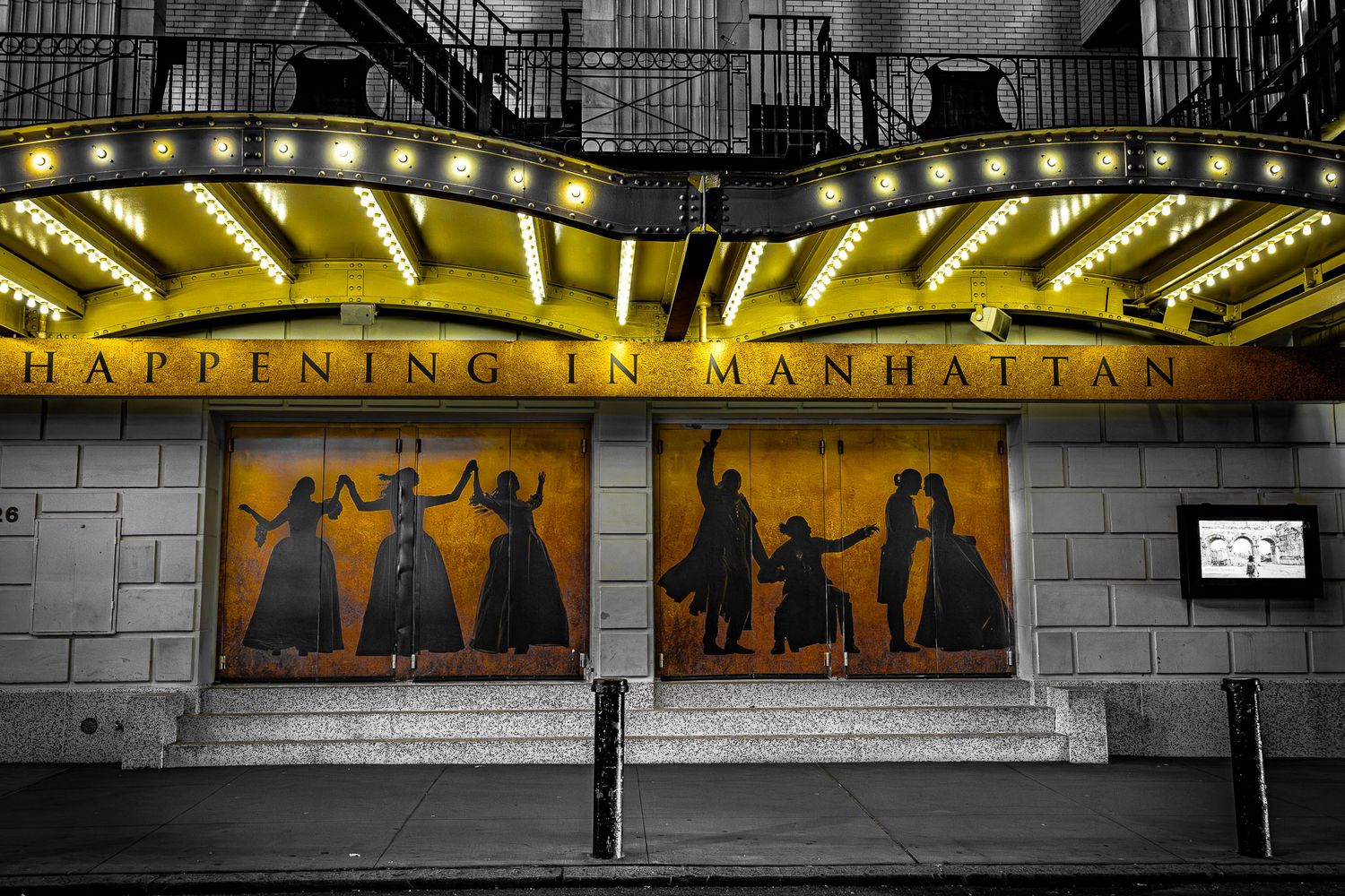 Theater marquee and doors illuminated at night in New York City’s Theater District near Times Square.