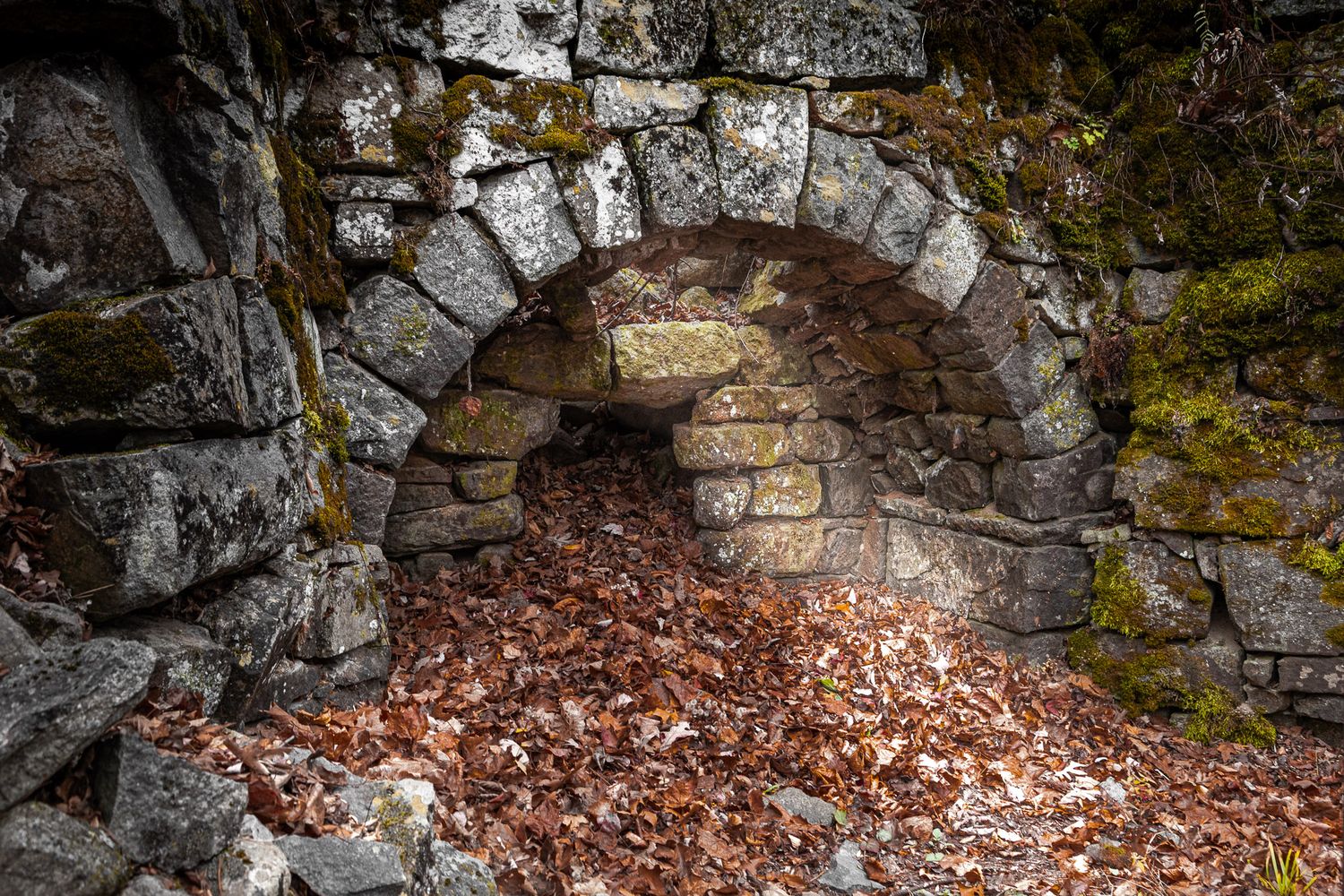 Historic lime kiln ruins at Stephens State Park in Hackettstown, New Jersey, built from stone and surrounded by fallen leaves.