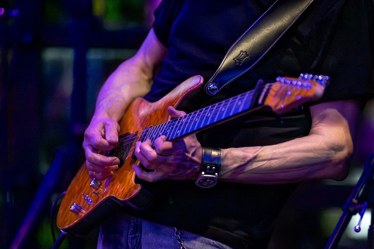 The Wrecks guitarist playing an electric guitar during a live performance, hands and instrument lit by stage lighting.