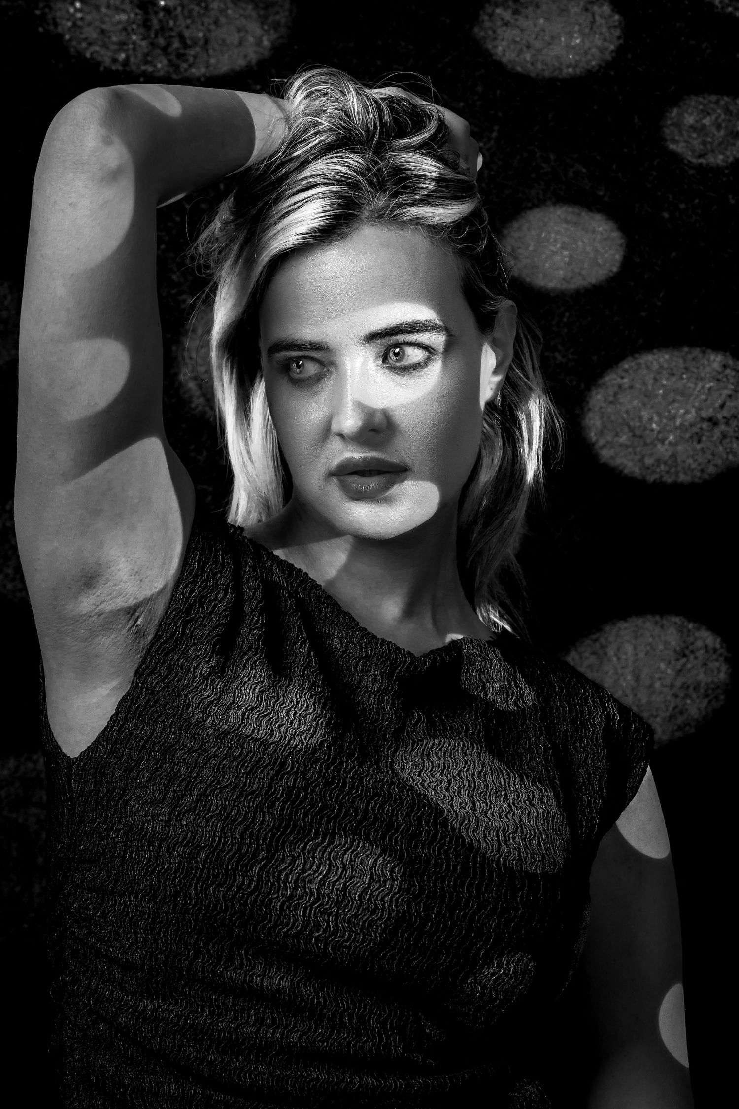 Black and white studio portrait of a woman with dramatic patterned light and shadow across her face and body. during a Unique Photo photogra