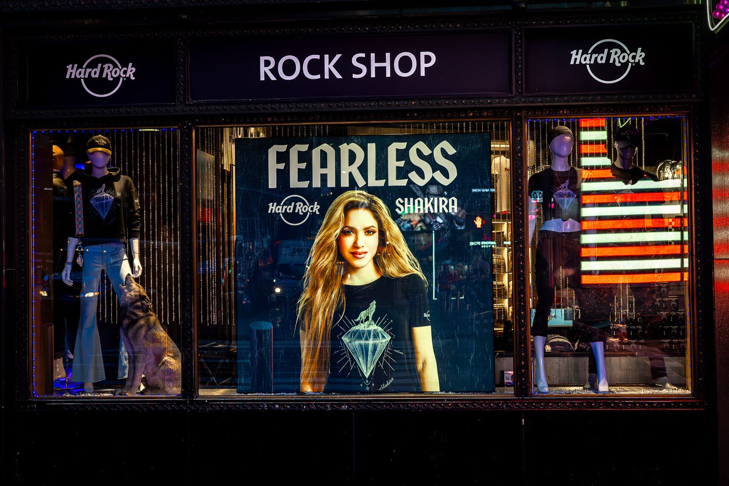 Hard Rock Rock Shop window display in Times Square featuring illuminated signage and a Fearless concert poster at night.