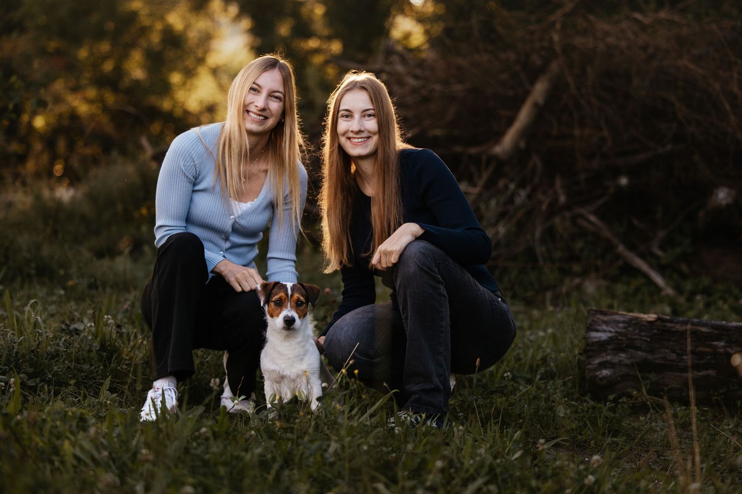 Friends enjoying time outdoors with their pet dogs during sunset.