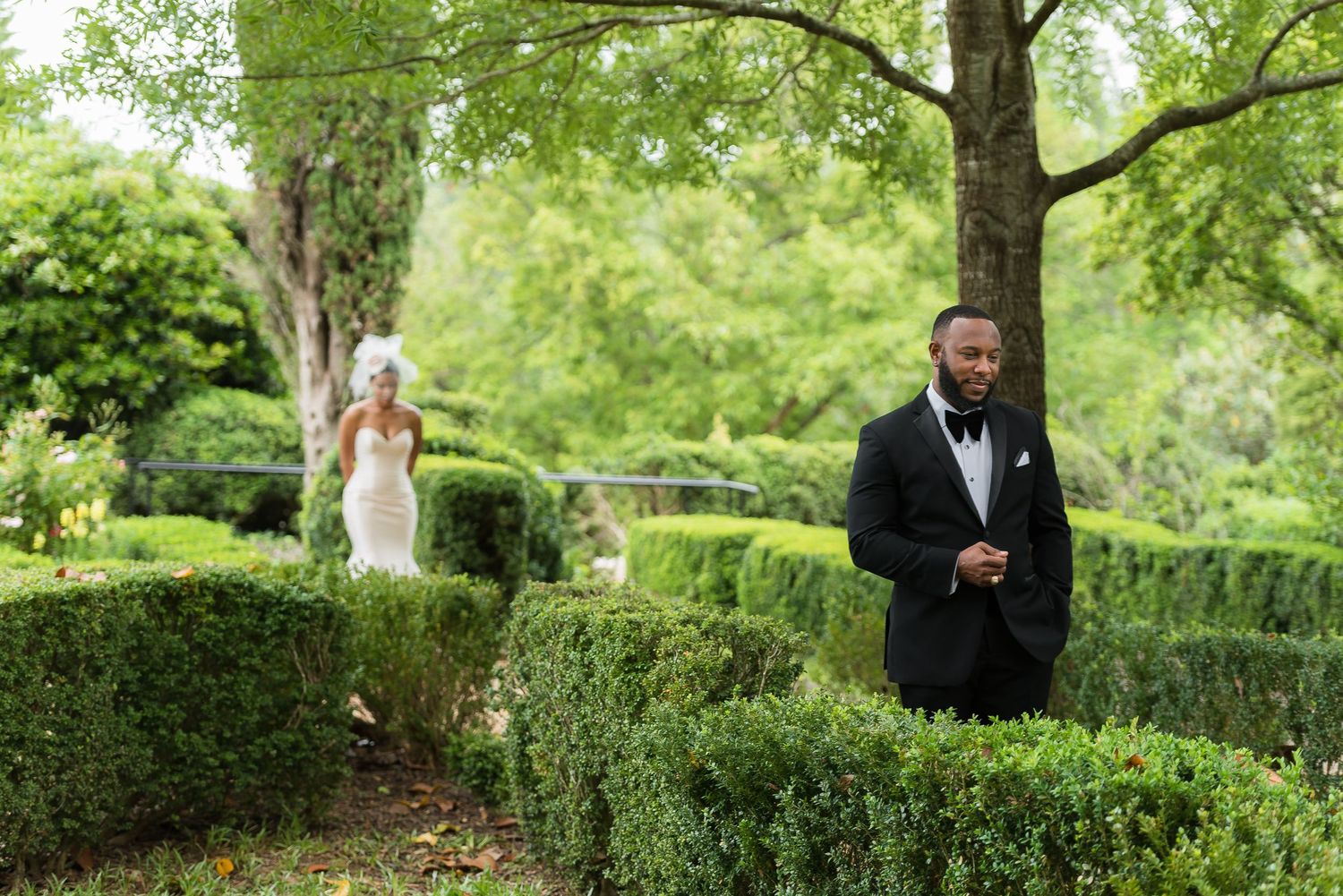 Hedge maze garden pathway with formal wedding party members walking through.