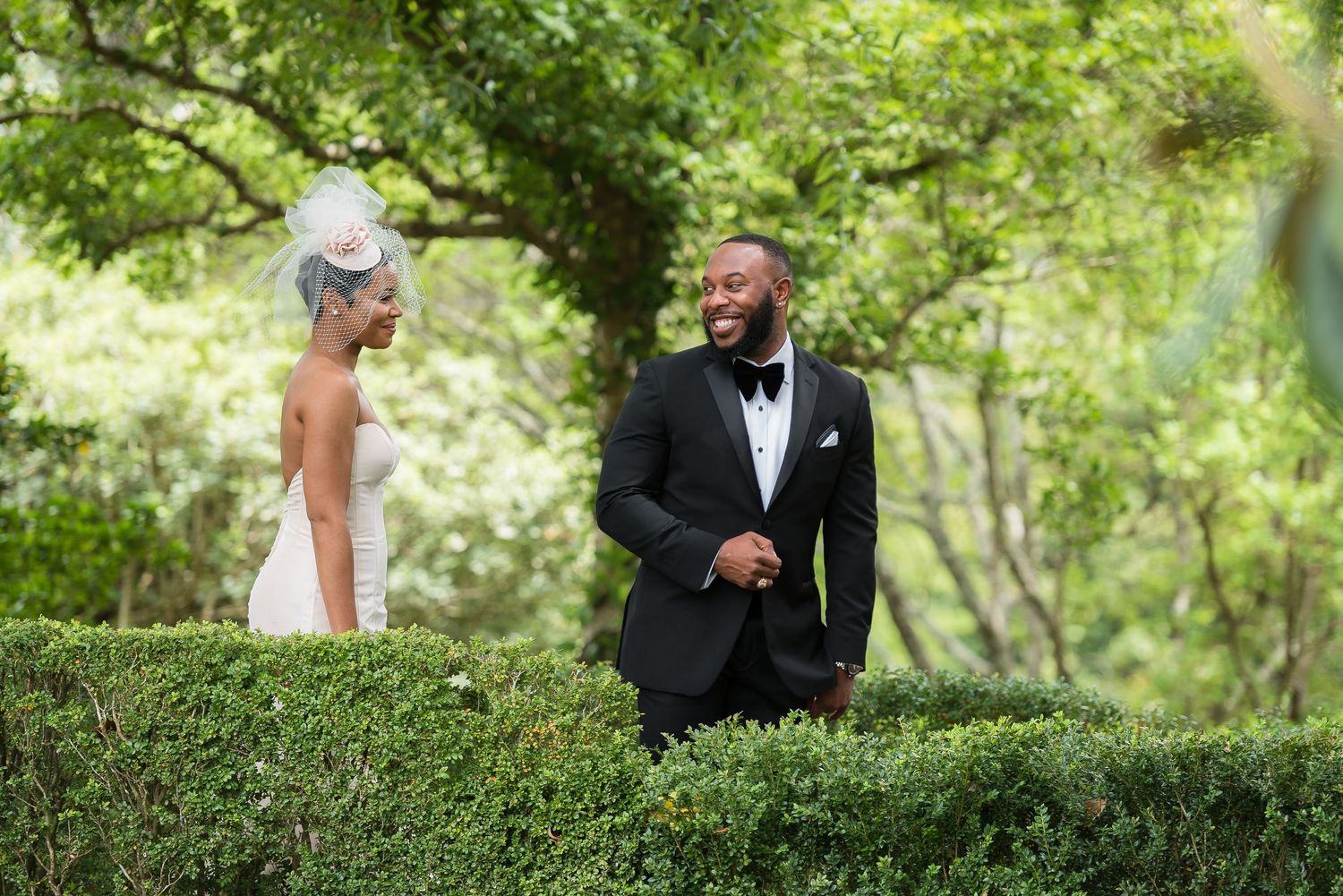 A romantic first look moment between newlyweds in a lush garden setting with greenery.