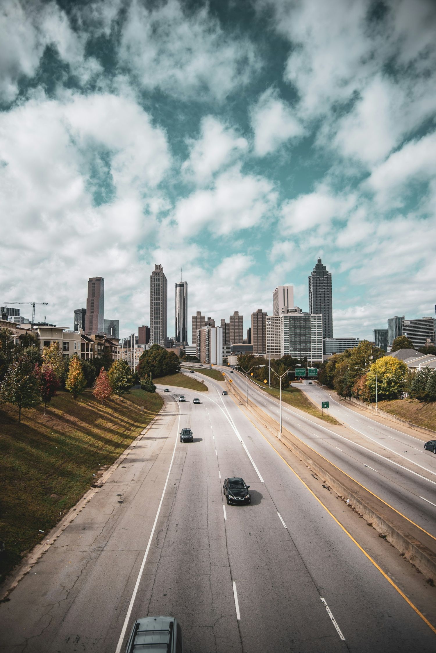 Dramatic cityscape of Atlanta skyline with empty highway and cloudy blue sky.