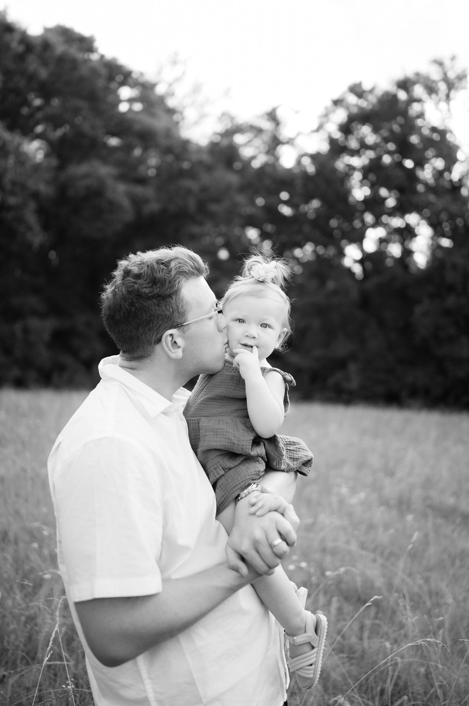 A tender moment between parent and child in a summer field captured in black and white.