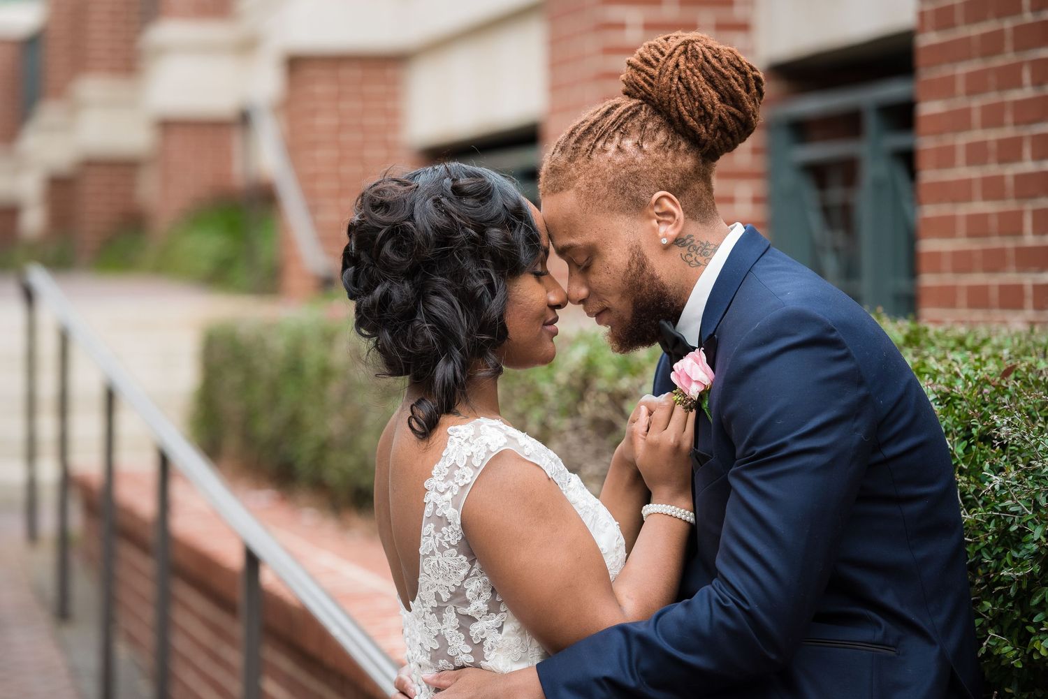 An intimate moment shared between a couple during their wedding day near a brick building.