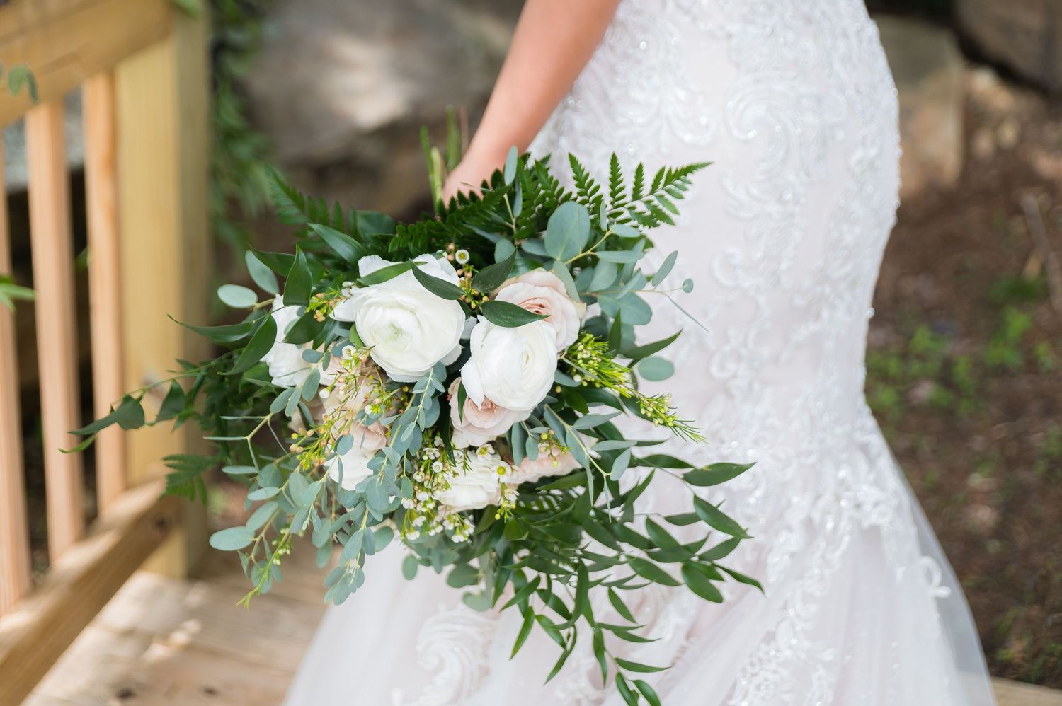A lush white and green wedding bouquet with roses and eucalyptus leaves.
