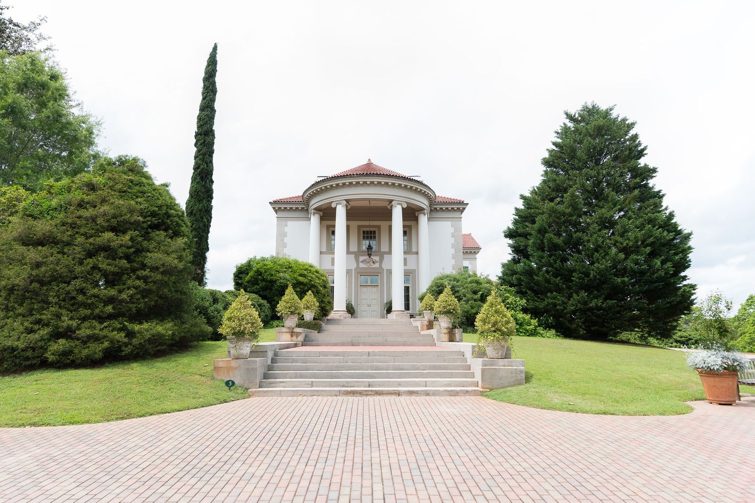 Sweeping panoramic view of a grand wedding venue with classical architecture and landscaping.