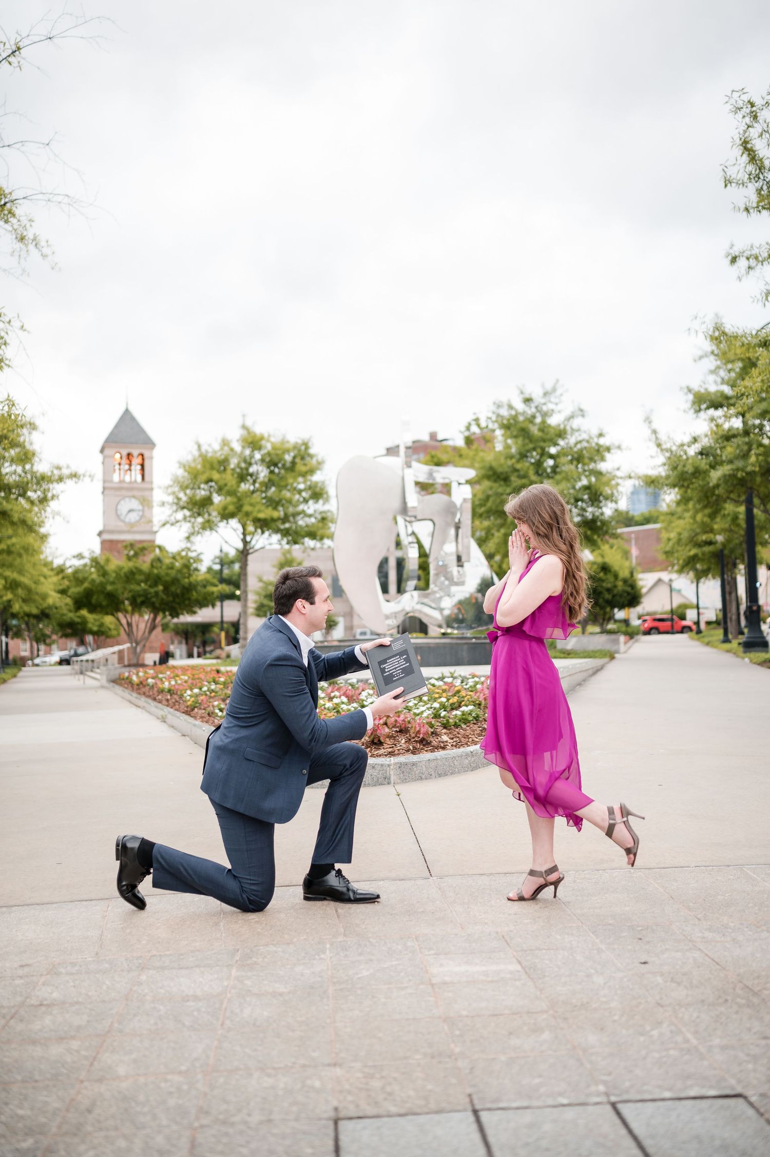 Marriage proposal scene with decorative garden and church tower in background.