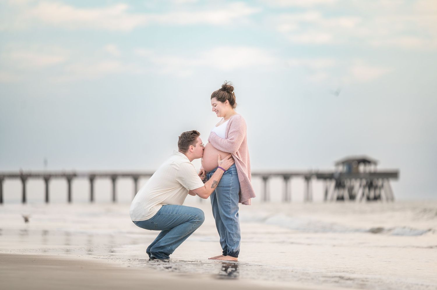 Beach engagement photography session against cloudy sky backdrop.