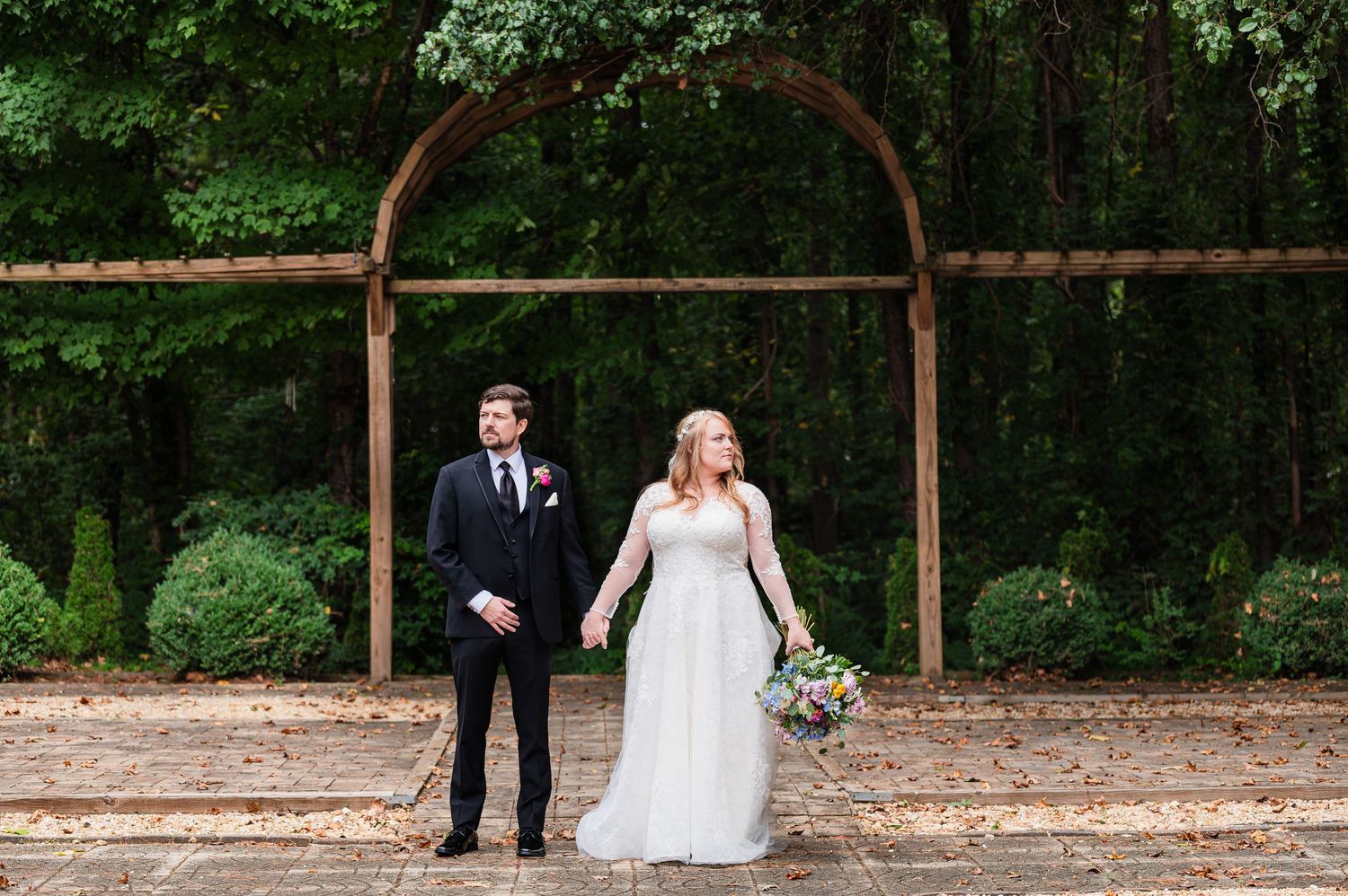 A wedding ceremony setup with a rustic wooden arch against a lush forest backdrop.
