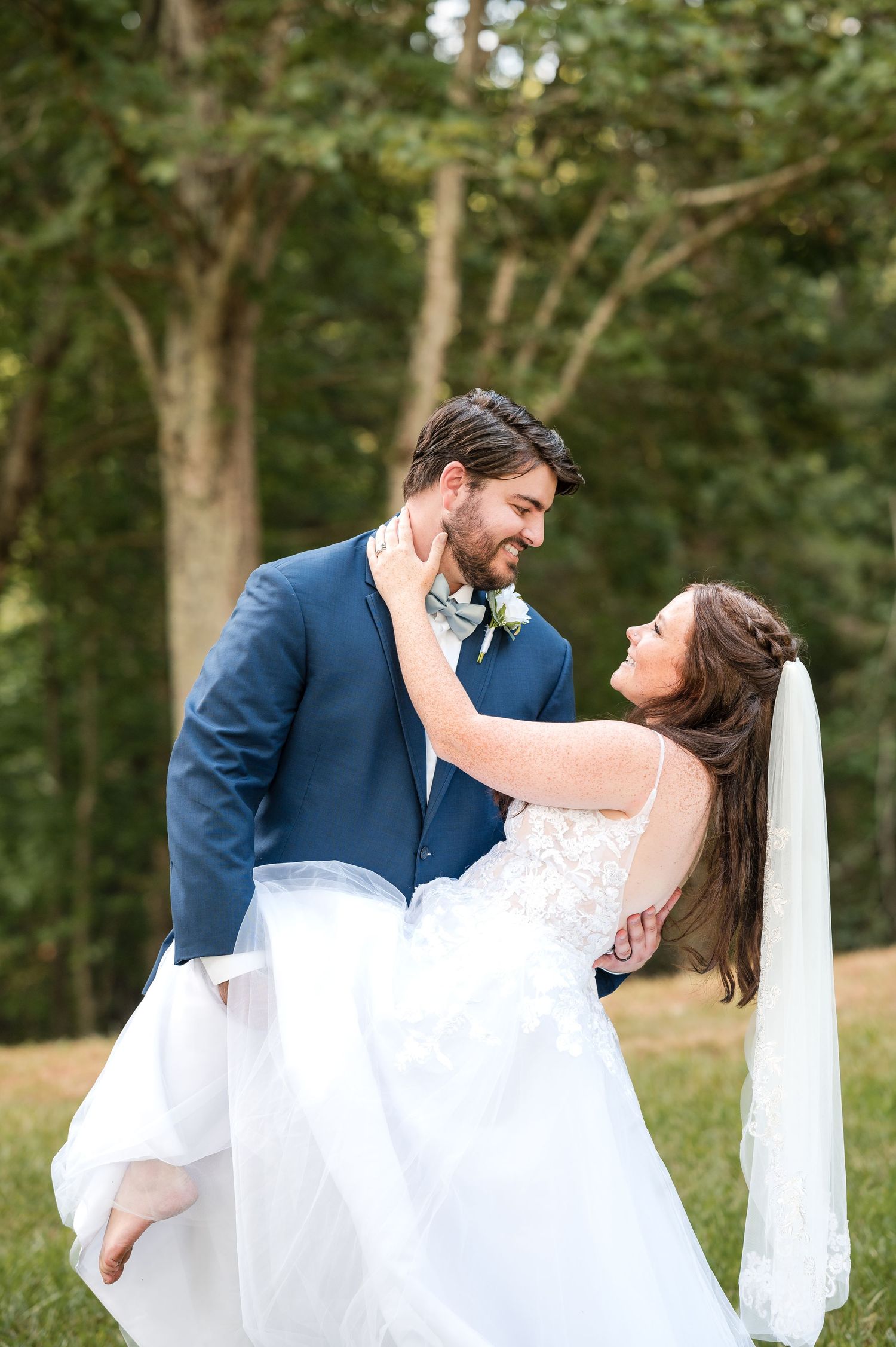 A romantic outdoor wedding moment captured in a wooded setting with natural lighting.