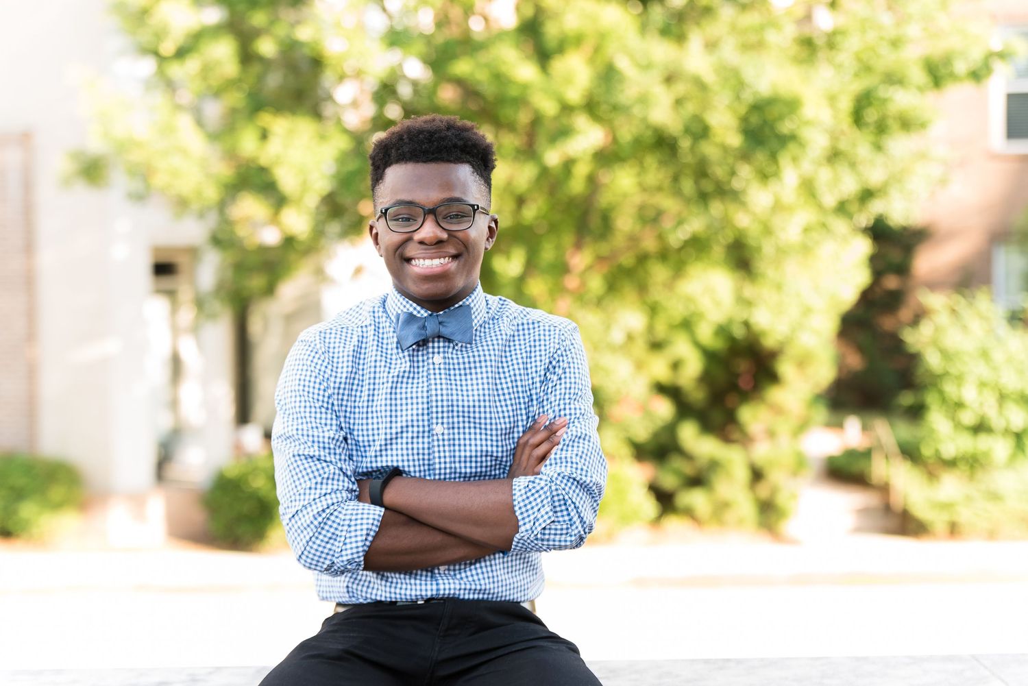 Professional portrait of a person in glasses and blue button-down shirt with arms crossed.