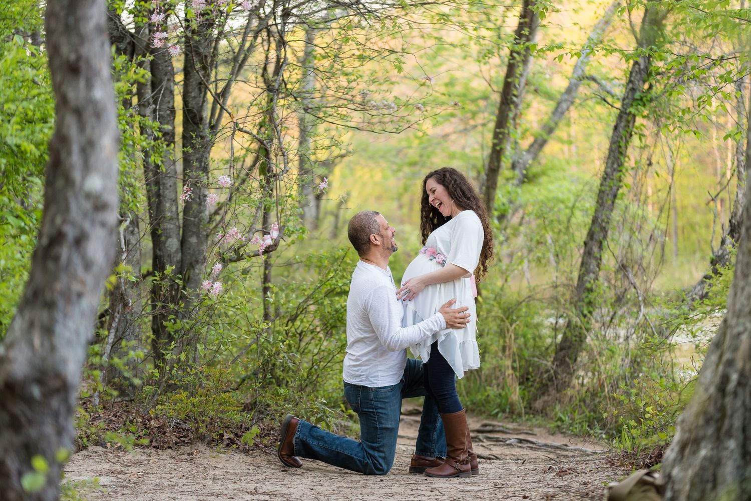 Spring engagement session in a sunlit forest with natural greenery.