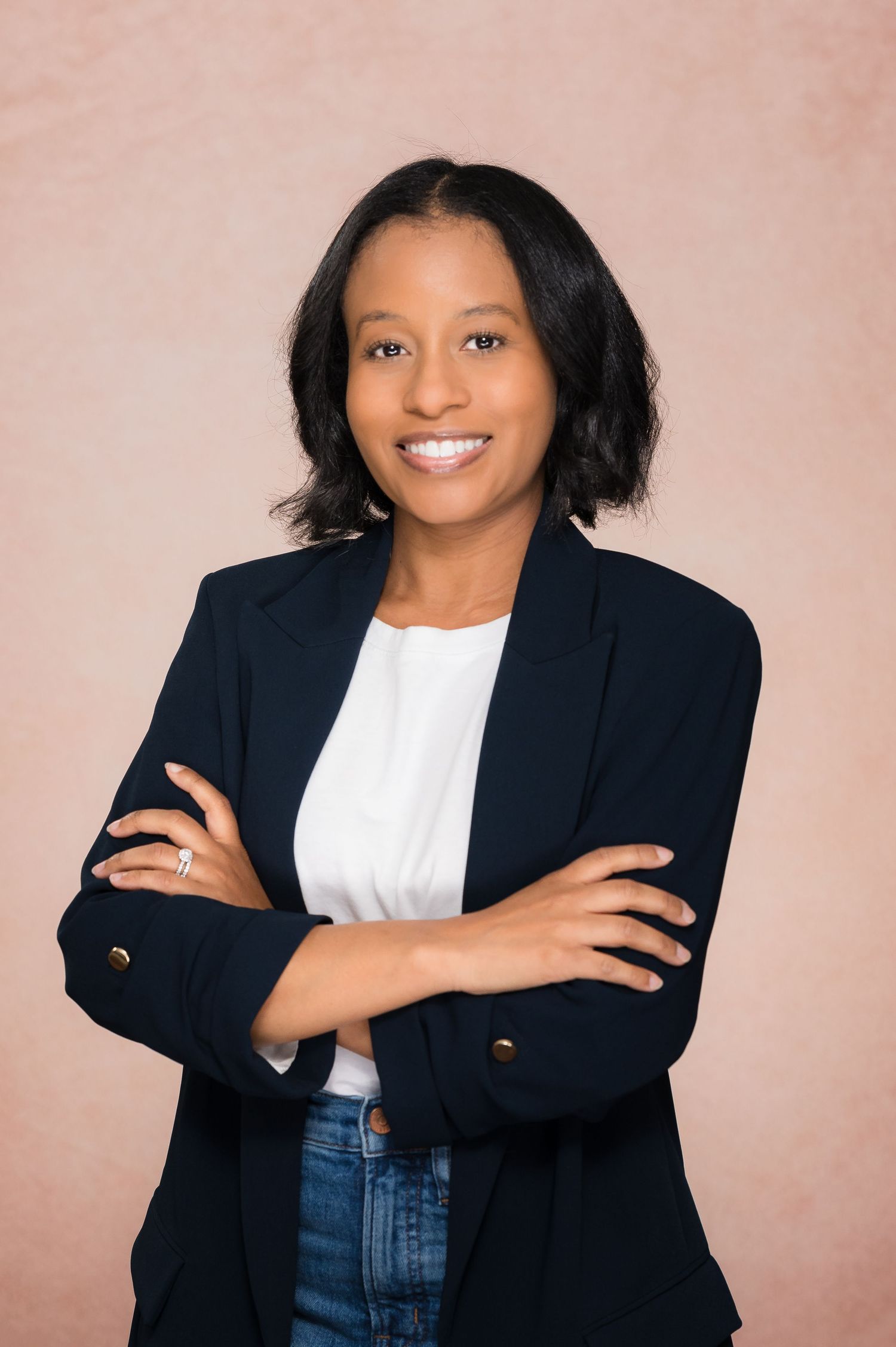 Professional studio portraits with navy blazer against pink backdrop.