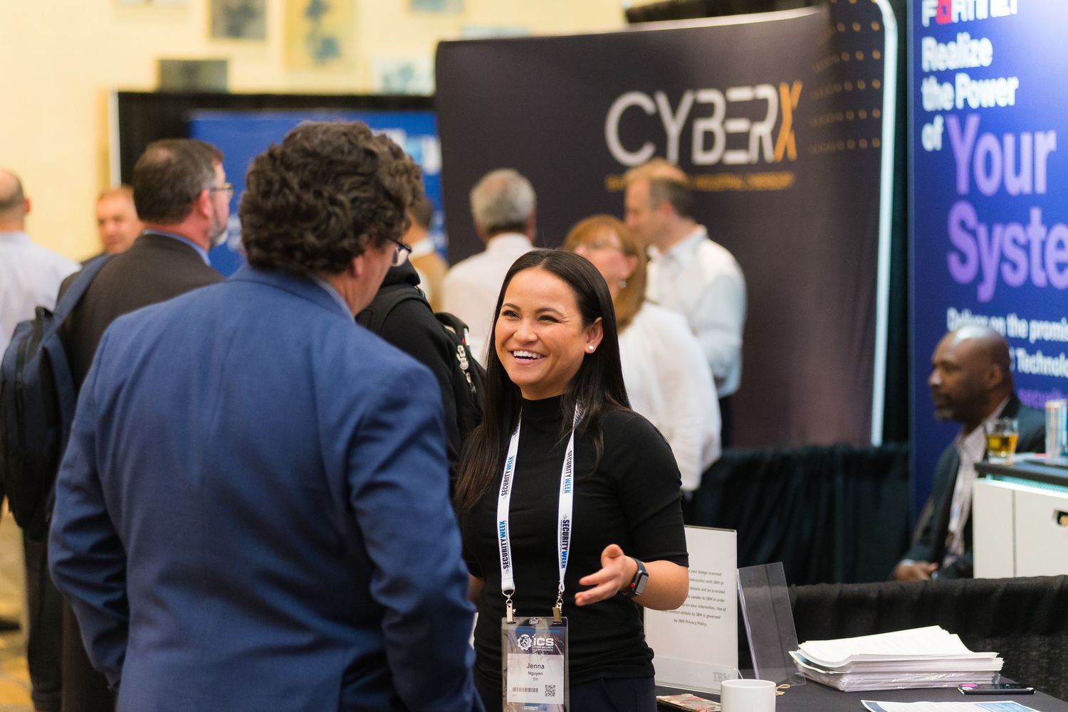 Business networking event with attendees mingling in front of branded displays.